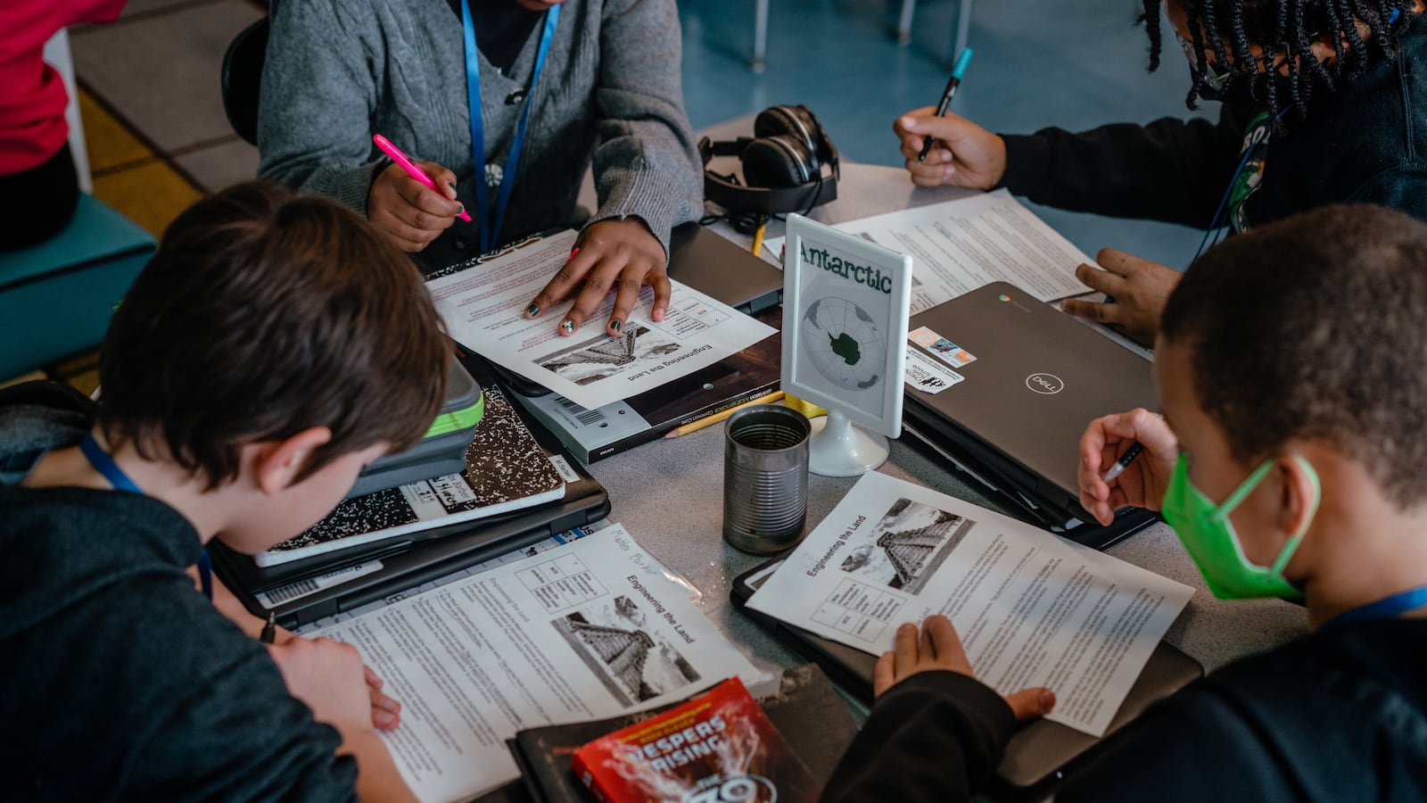 A group of four students work on worksheets together at their desks.