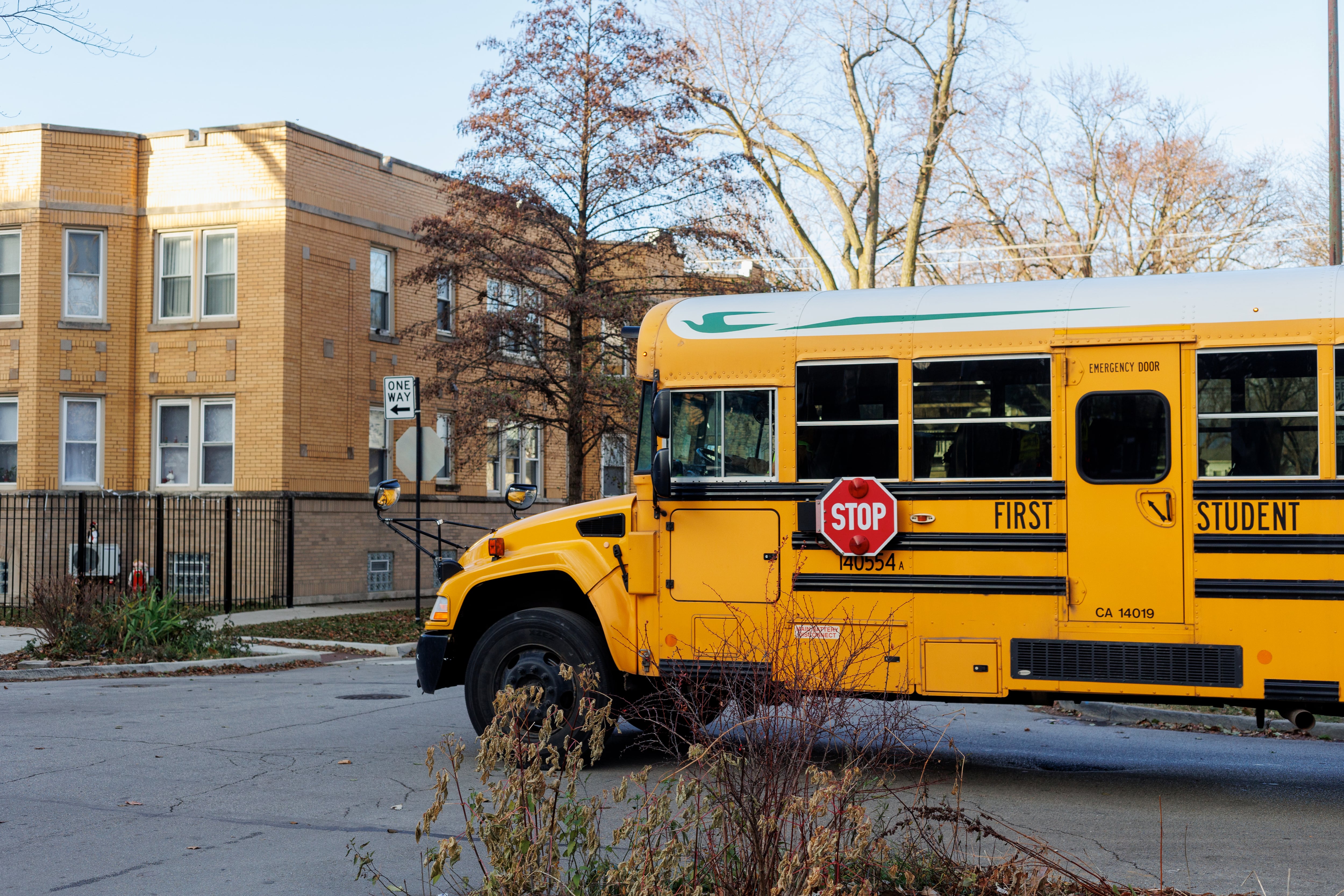 A yellow school bus turns a corner in a neighborhood.
