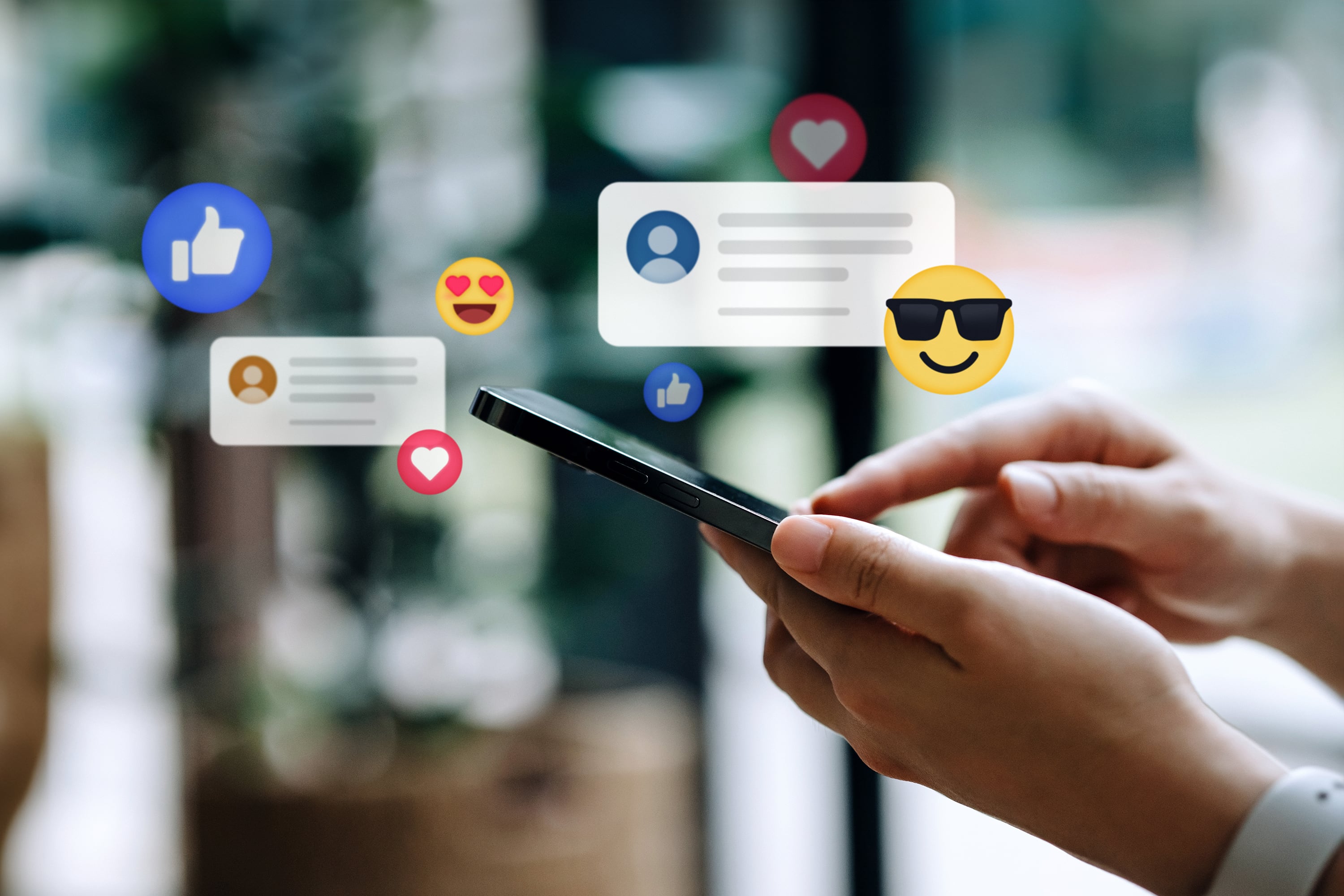 Close up of a person's hands holding a cellphone with illustrations of emojis and chat boxes popping out from the phone.