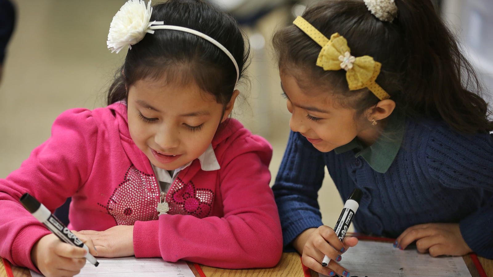 Kindergartners Ivania, left, and Jackie work on reading and writing at Enlace Academy.