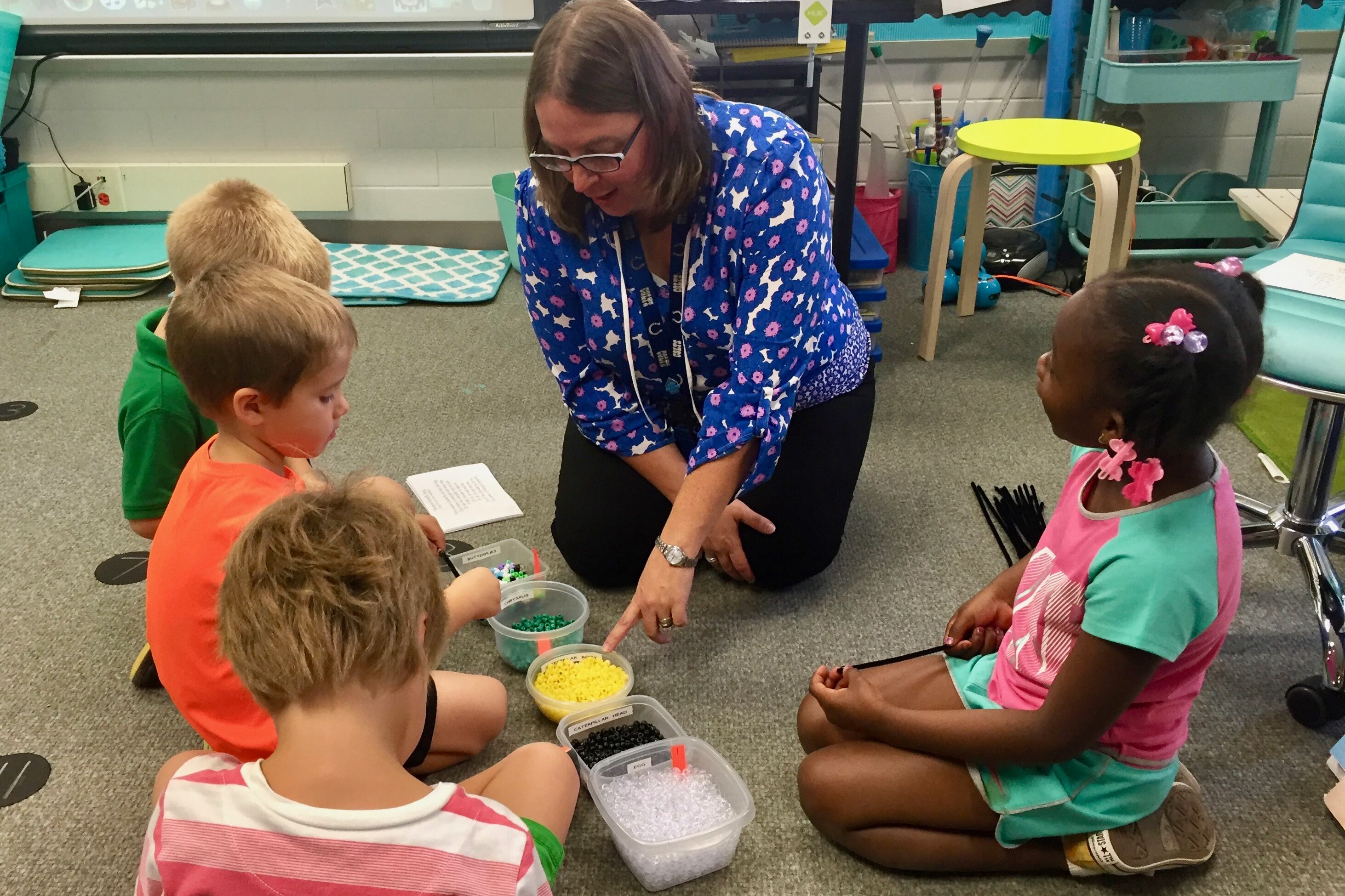 Kristin Poindexter helps her kindergarten students assemble butterfly bracelets in her science class at Spring Mill Elementary School in Washington Township.
