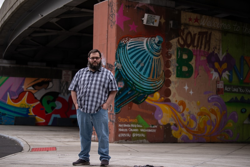 A man stands in front of a colorful mural.