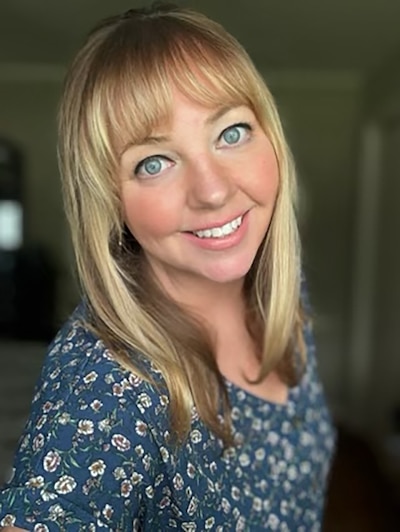 A woman with long blonde hair poses in a selfie inside.