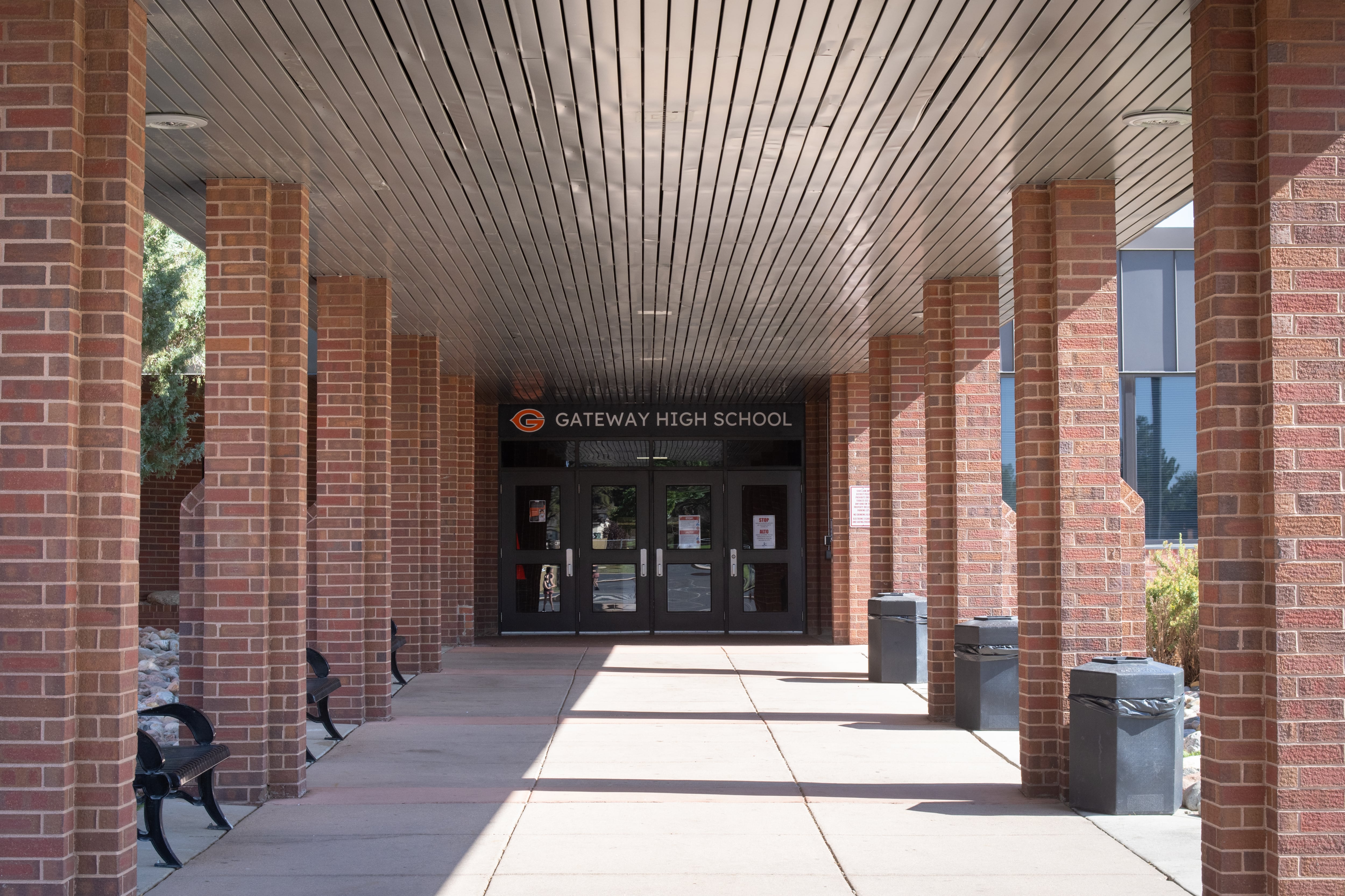 An outdoor corridor with brick pillars leads up to a school entrance. A sign over the door reads Gateway High School.