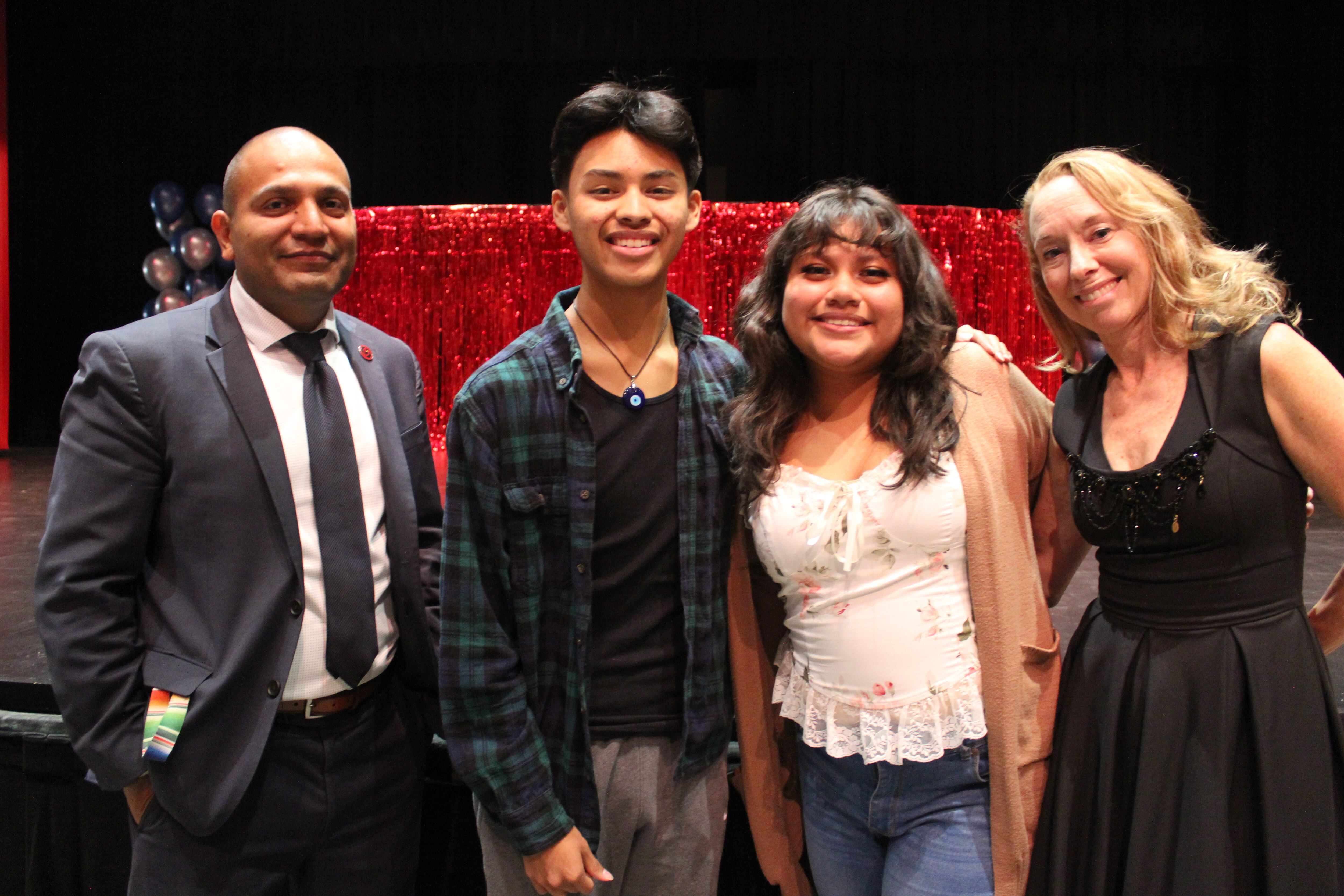 Two adults and two students stand in an auditorium at Curie Metropolitan High School in Chicago’s Archer Heights neighborhood.