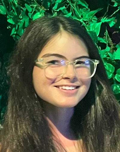 A portrait of a girl with long dark hair and clear glasses.