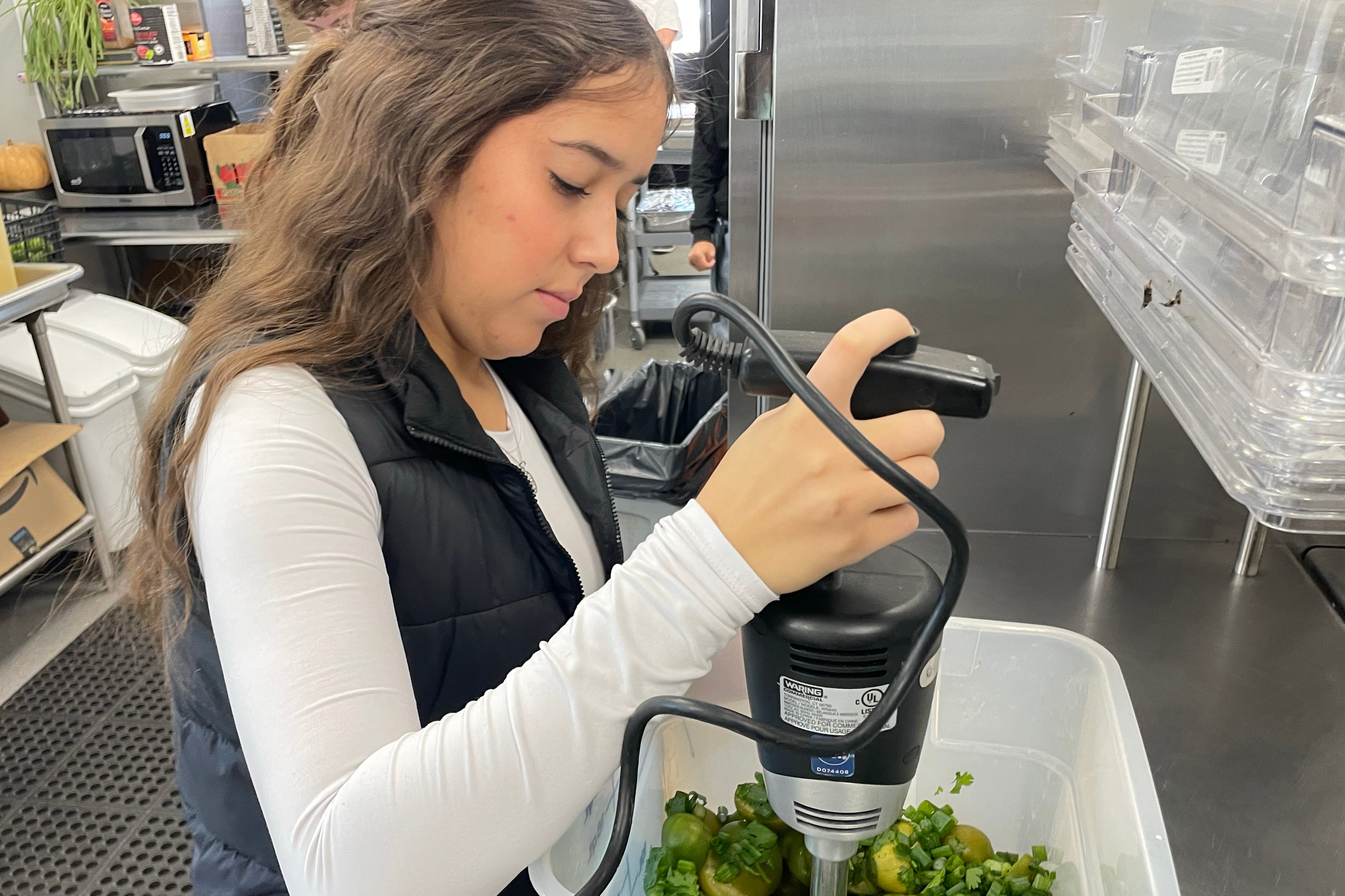 A high school student uses an immersion blender.