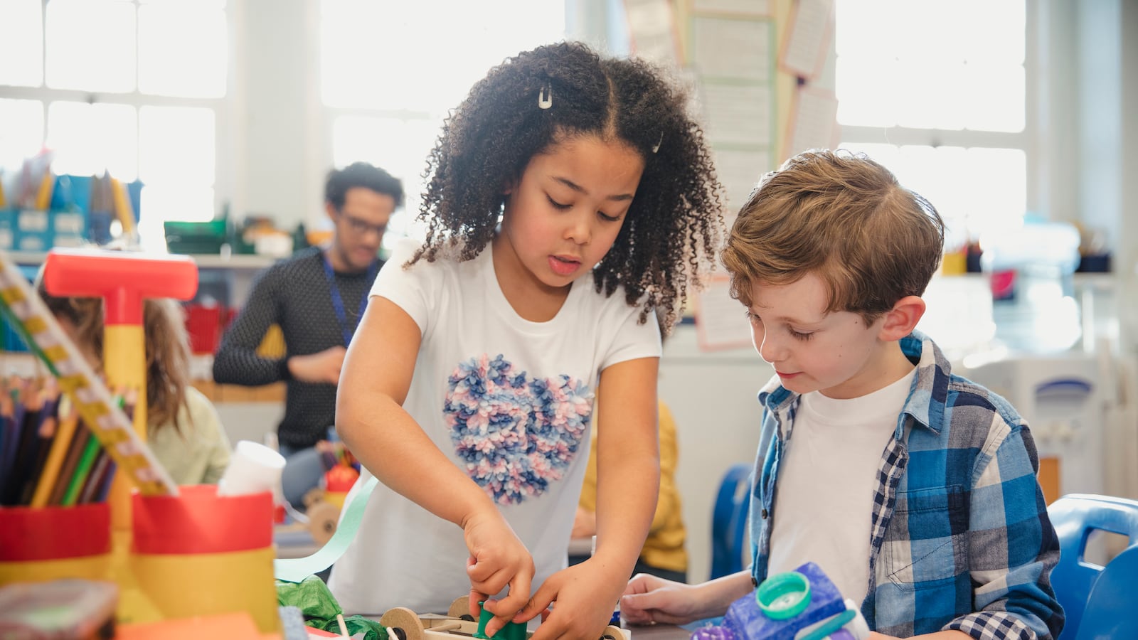 Photo of two elementary school students building models with recycled materials.