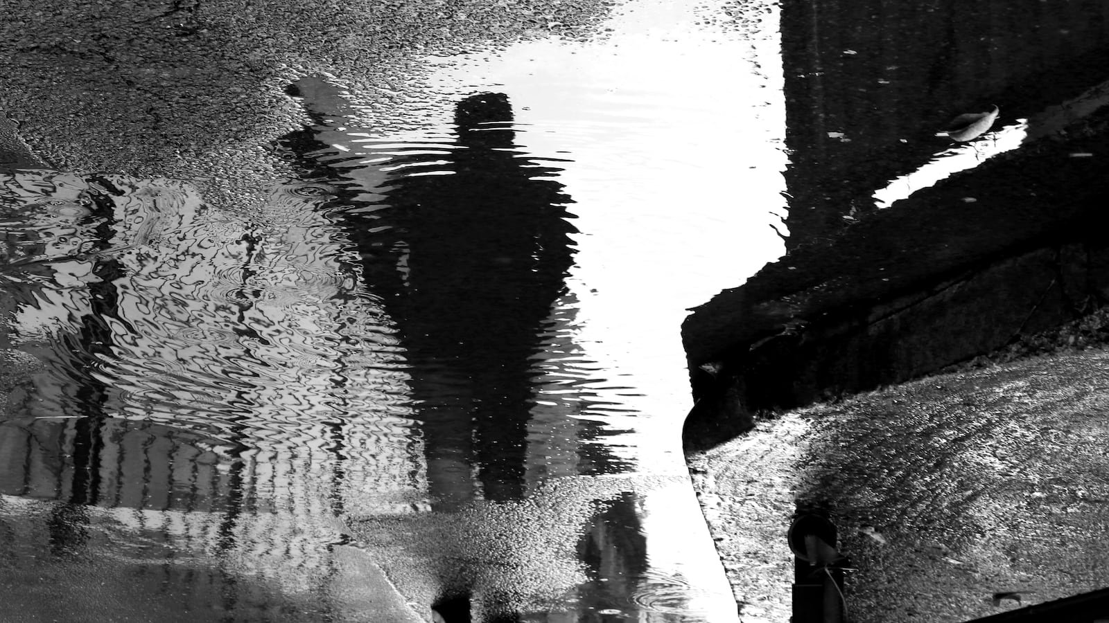 A distorted black and white image of a man walking on the street.