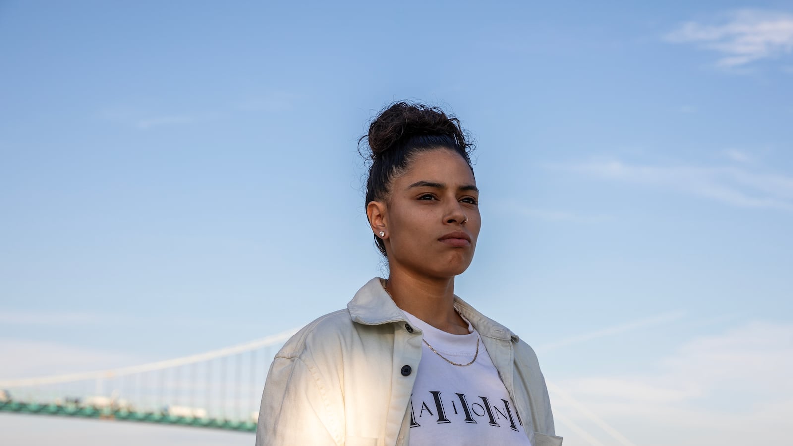 A woman in white with her hair in a bun looks off to the side.