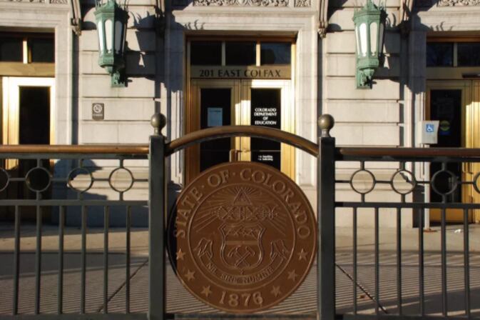 The front entrance of a building with a large copper looking seal.