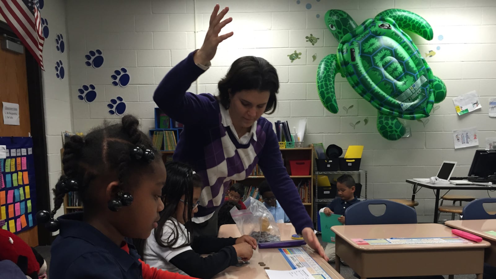 Shana Nissenbaum, a third-grade teacher at the now-closed Key Learning Community School, helps a group of students with a math activity on counting money.