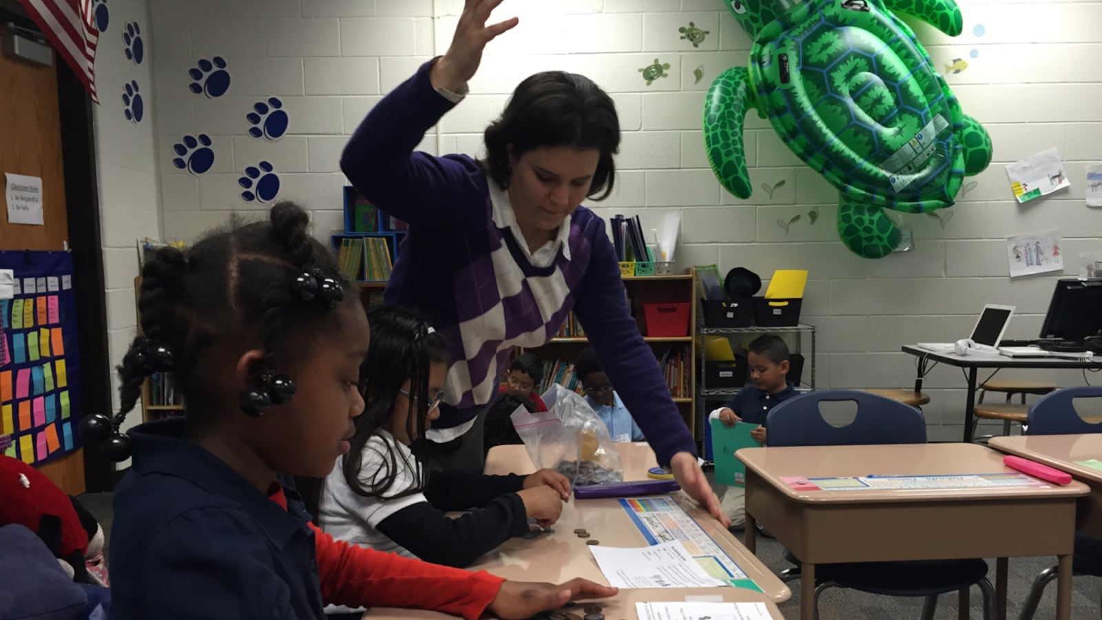 Shana Nissenbaum, a third-grade teacher at the now-closed Key Learning Community School, helps a group of students with a math activity on counting money.