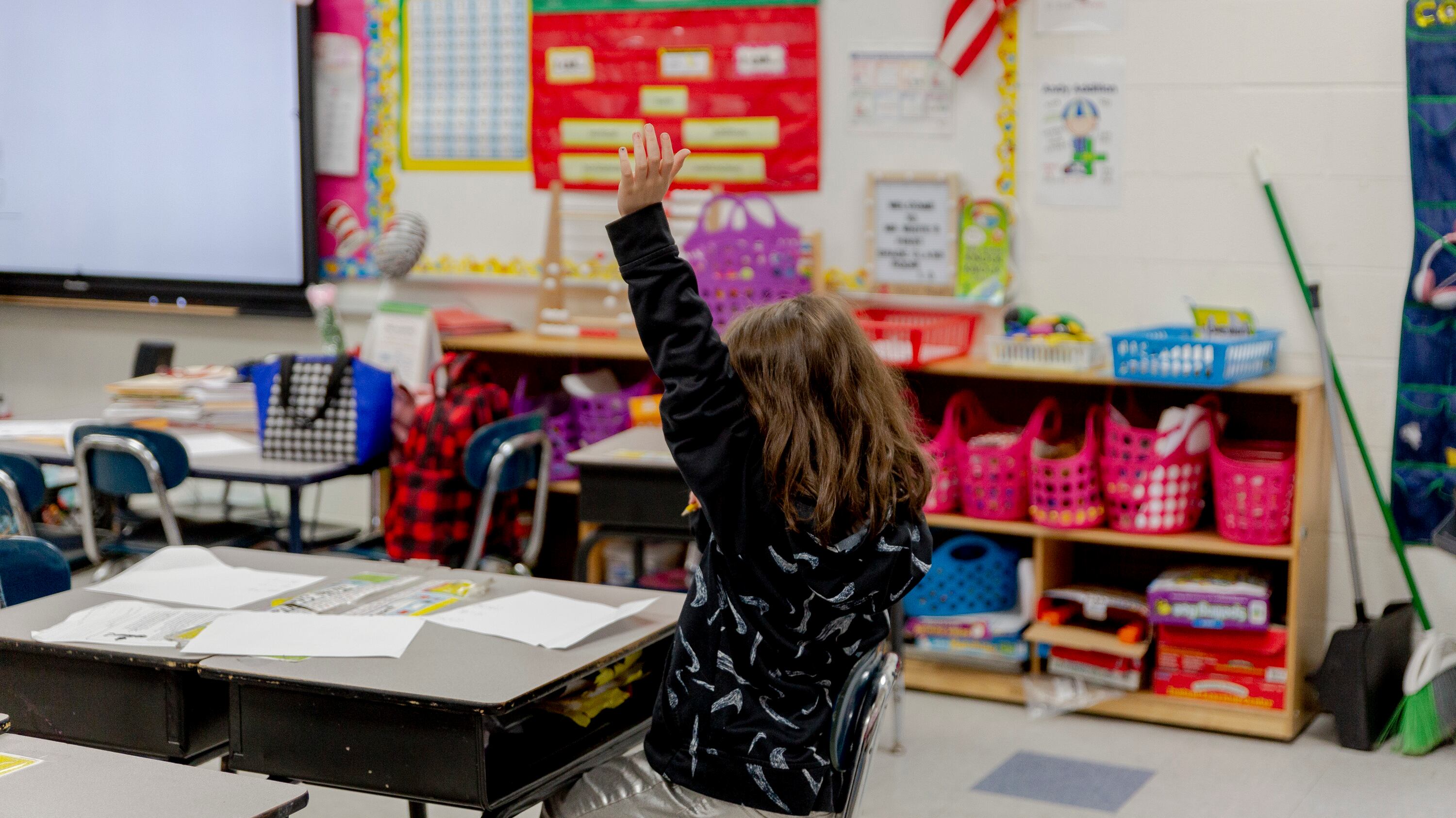 A second-grader raises her hand in a classroom.