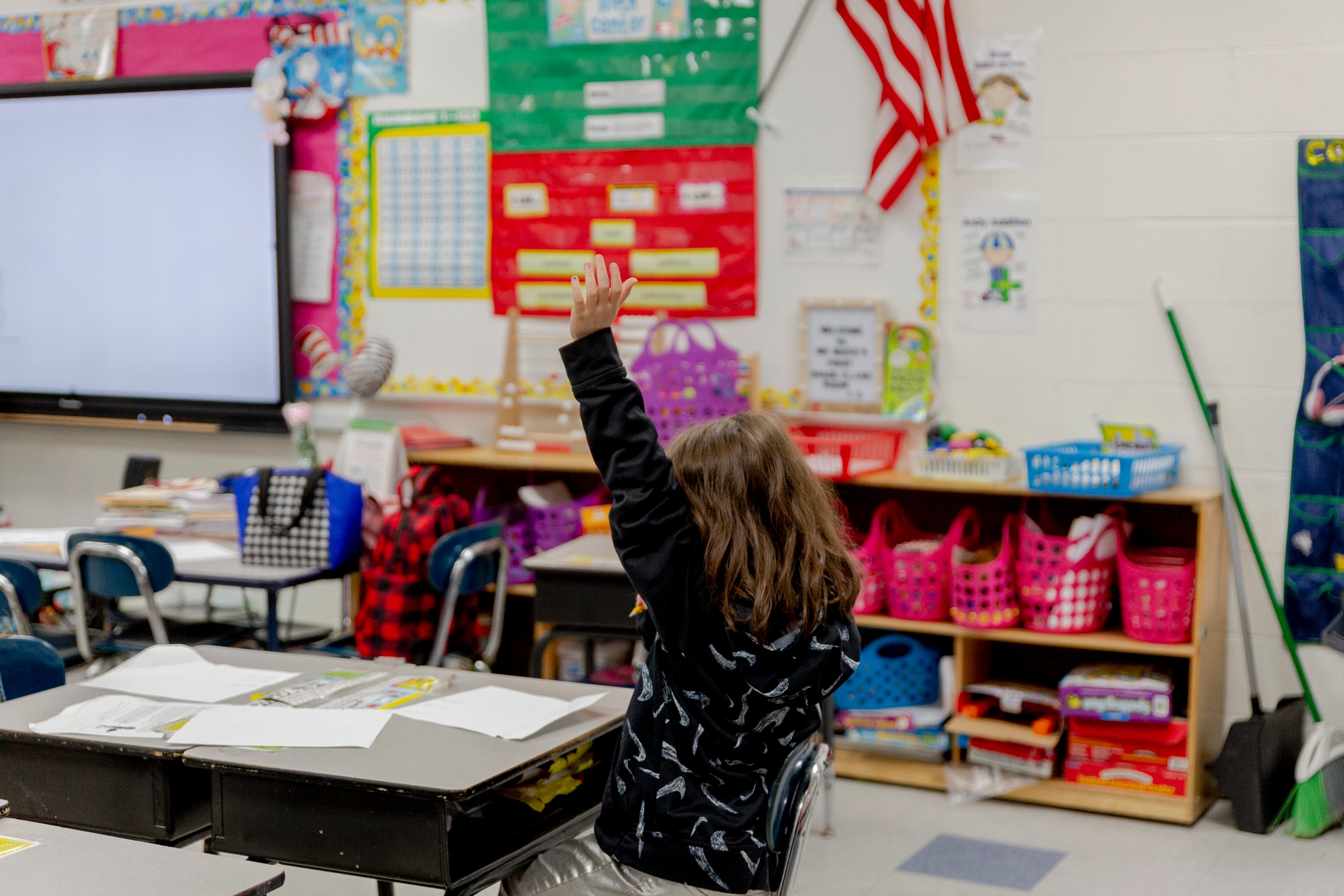 A second-grader raises her hand in a classroom.