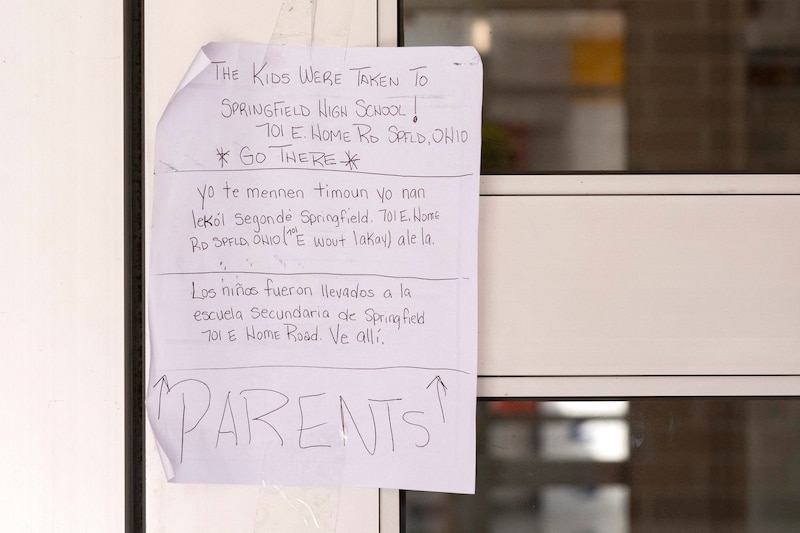 A close up of a handwritten note on a door of a school building.