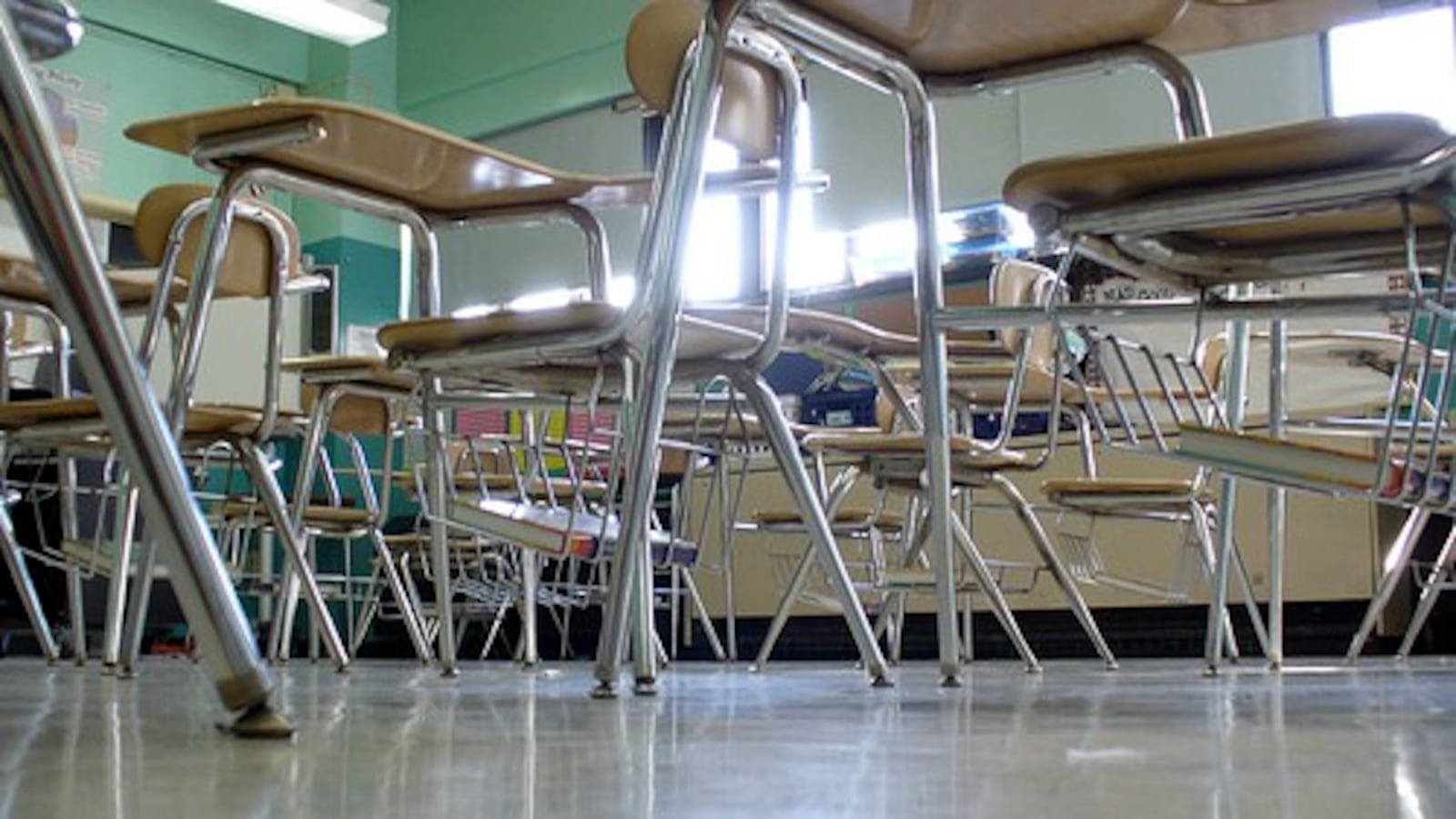 A classroom with green walls and empty desks.