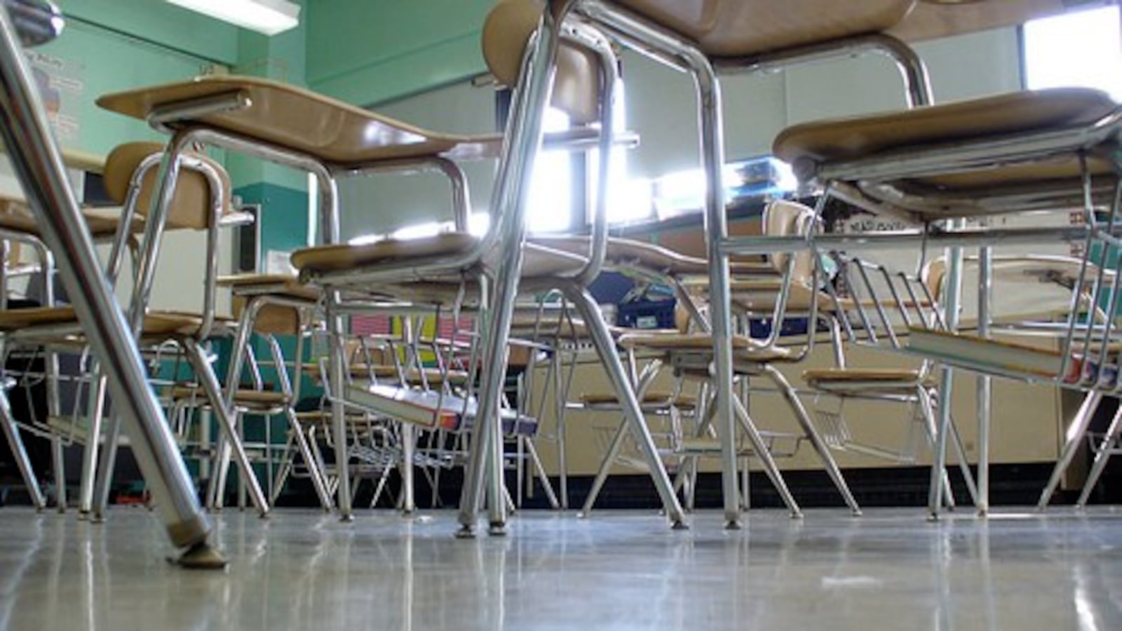 A classroom with green walls and empty desks.  