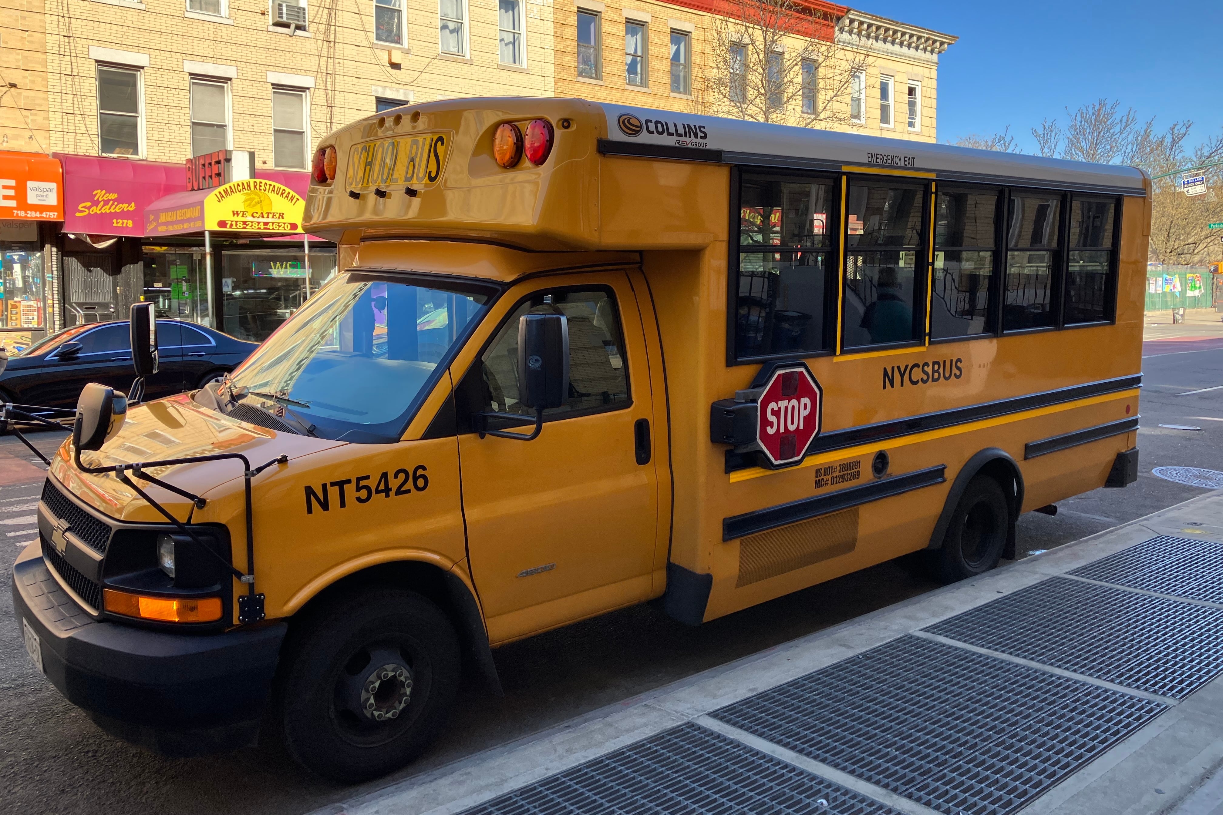 A New York City yellow school bus is parked next to the sidewalk.