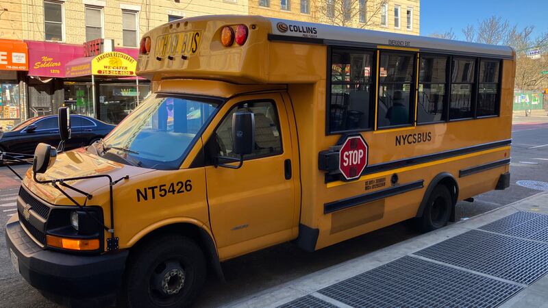 A New York City yellow school bus is parked next to the sidewalk.