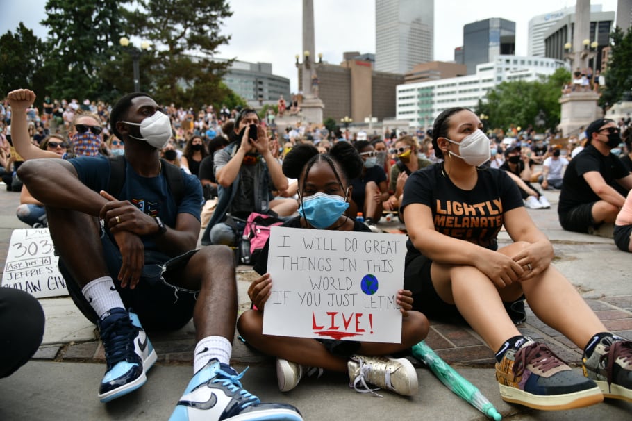 Sanaa Smith-Shabazz, 8, sits between her parents Ibn Shabazz, left, and Sidney Smith-Shabazz during a gathering at Civic Center Park in Denver on Thursday, June 4, 2020.