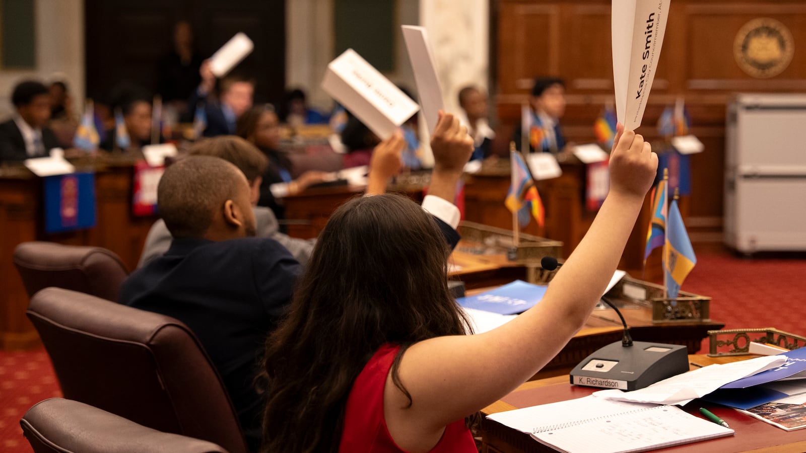 A photograph of participants of the youth summit sitting inside the circle holding up their nameplates to vote.