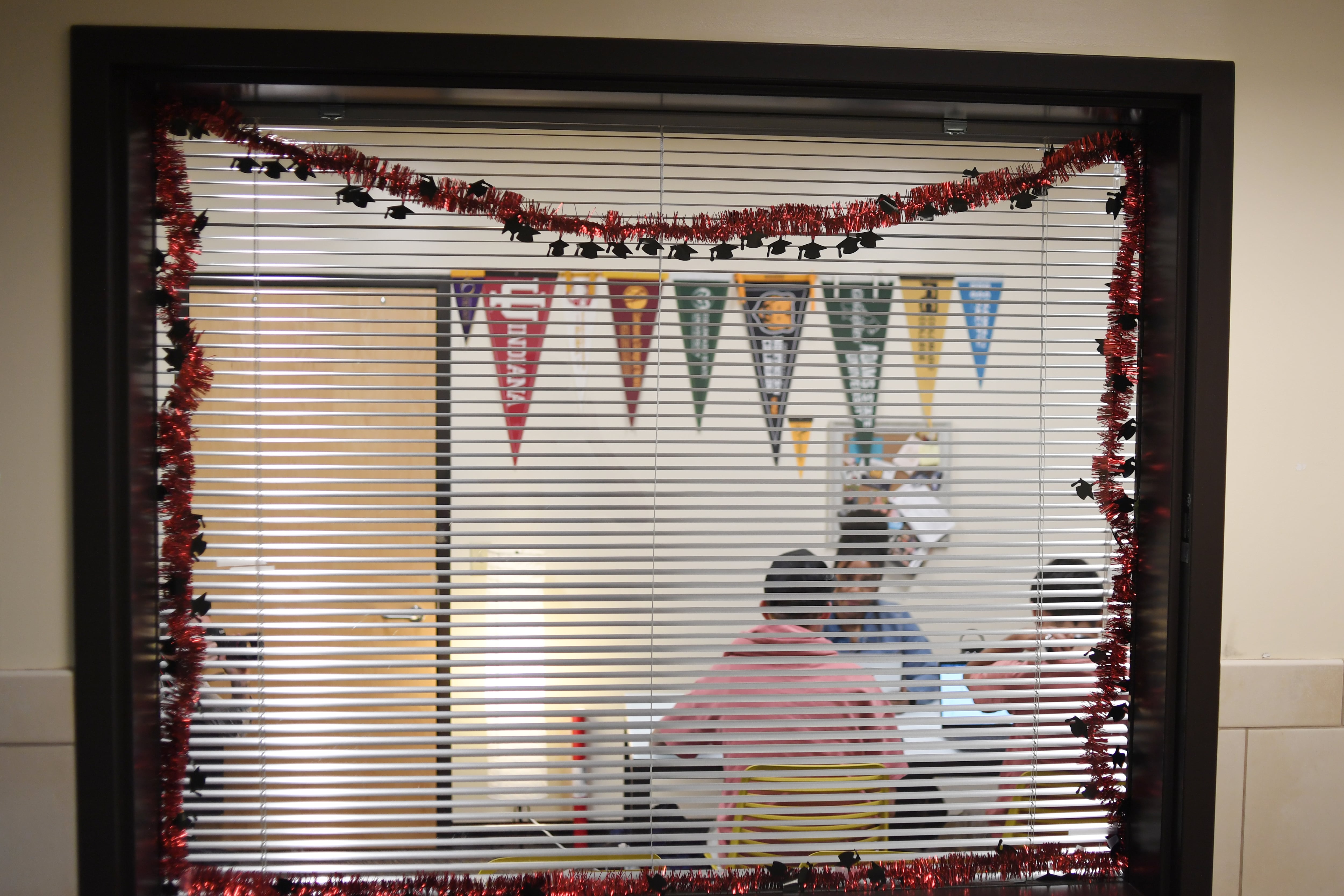 Students speak with a career counselor, seen behind a window with white blinds.