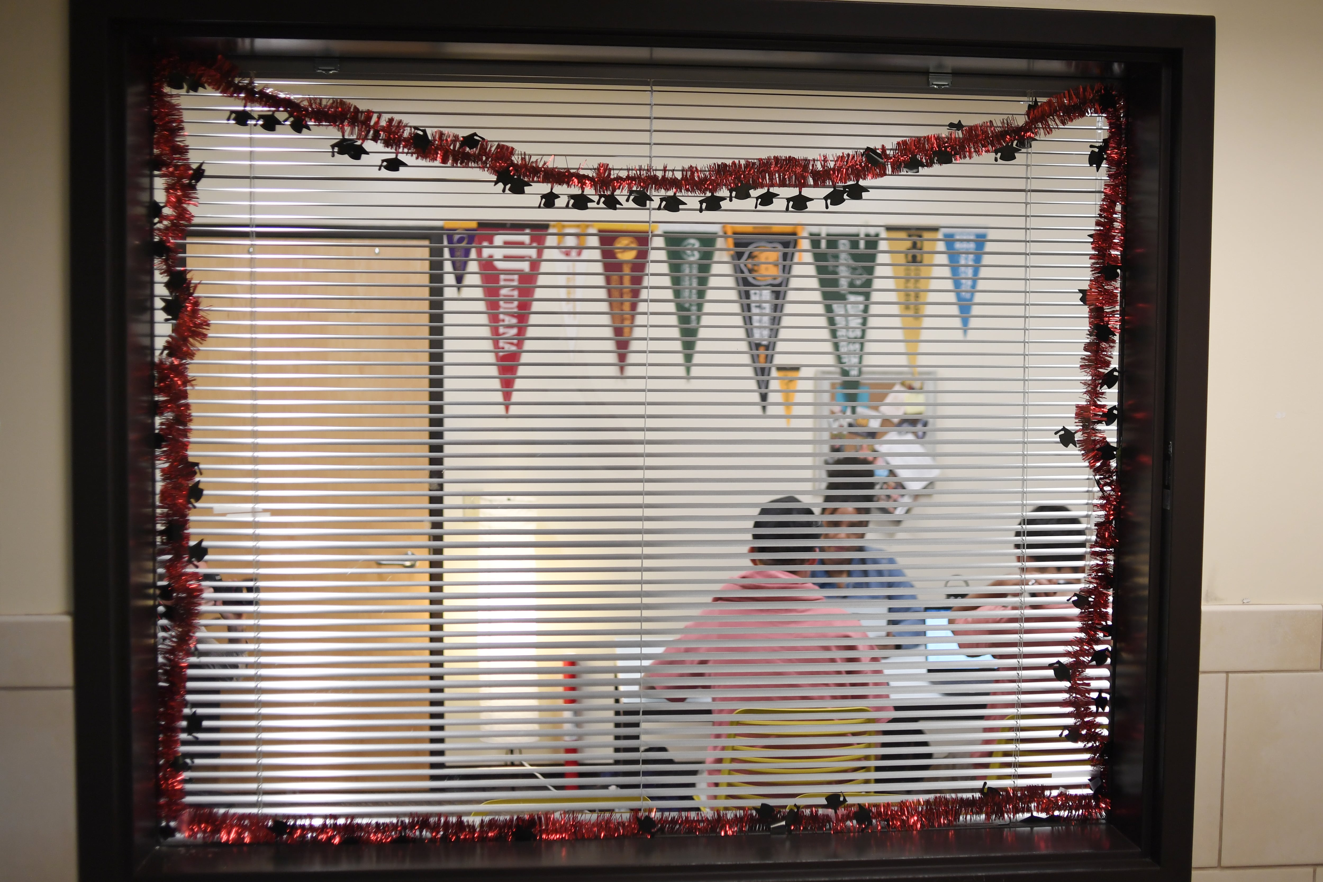 Students speak with a career counselor, seen behind a window with white blinds.