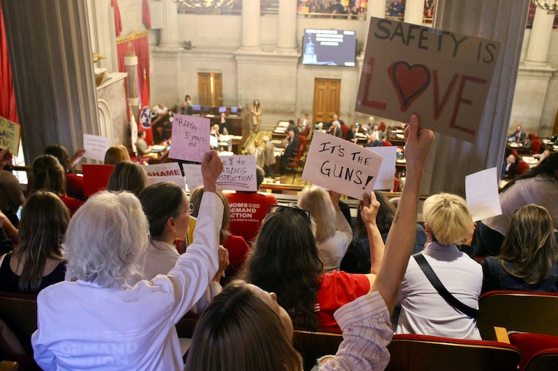 A large crowd gathers on the second level in the Tennessee House of Representatives building holding protest signs.