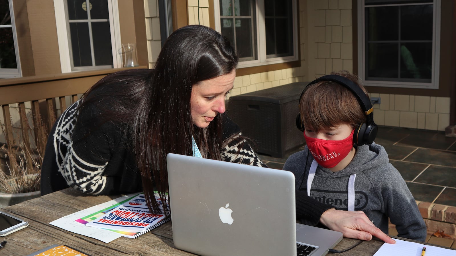 Angela Atkins helps her son Jess Atkins work on a math problem on his laptop during home schooling.