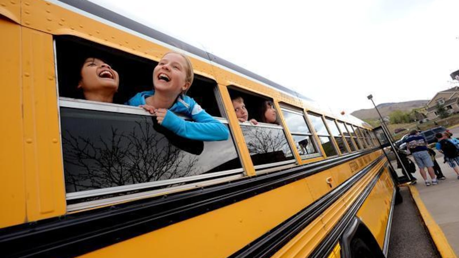 Fourth-graders Kintan Surghani, left, and Rachel Anderson laugh out the school bus window at Mitchell Elementary School in Golden.
