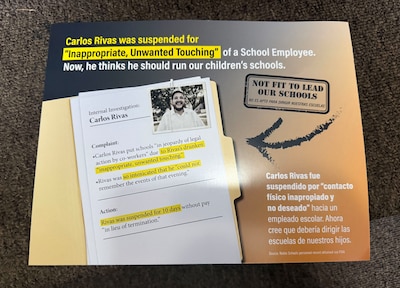 A campaign mailer with a photo and writing on it sits on the ground.