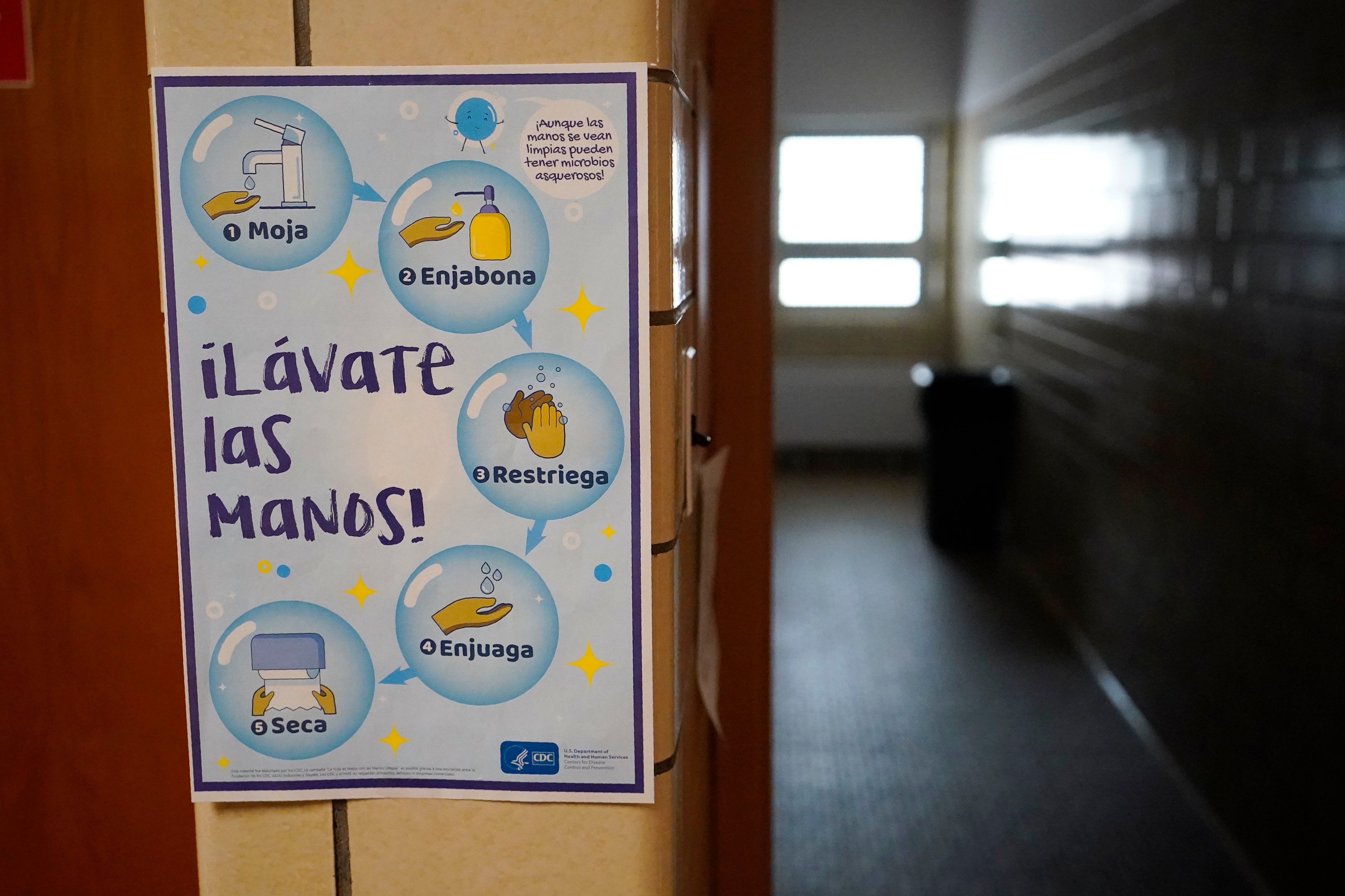 Spanish-language sign hung outside a school bathroom encourages children to wash their hands.