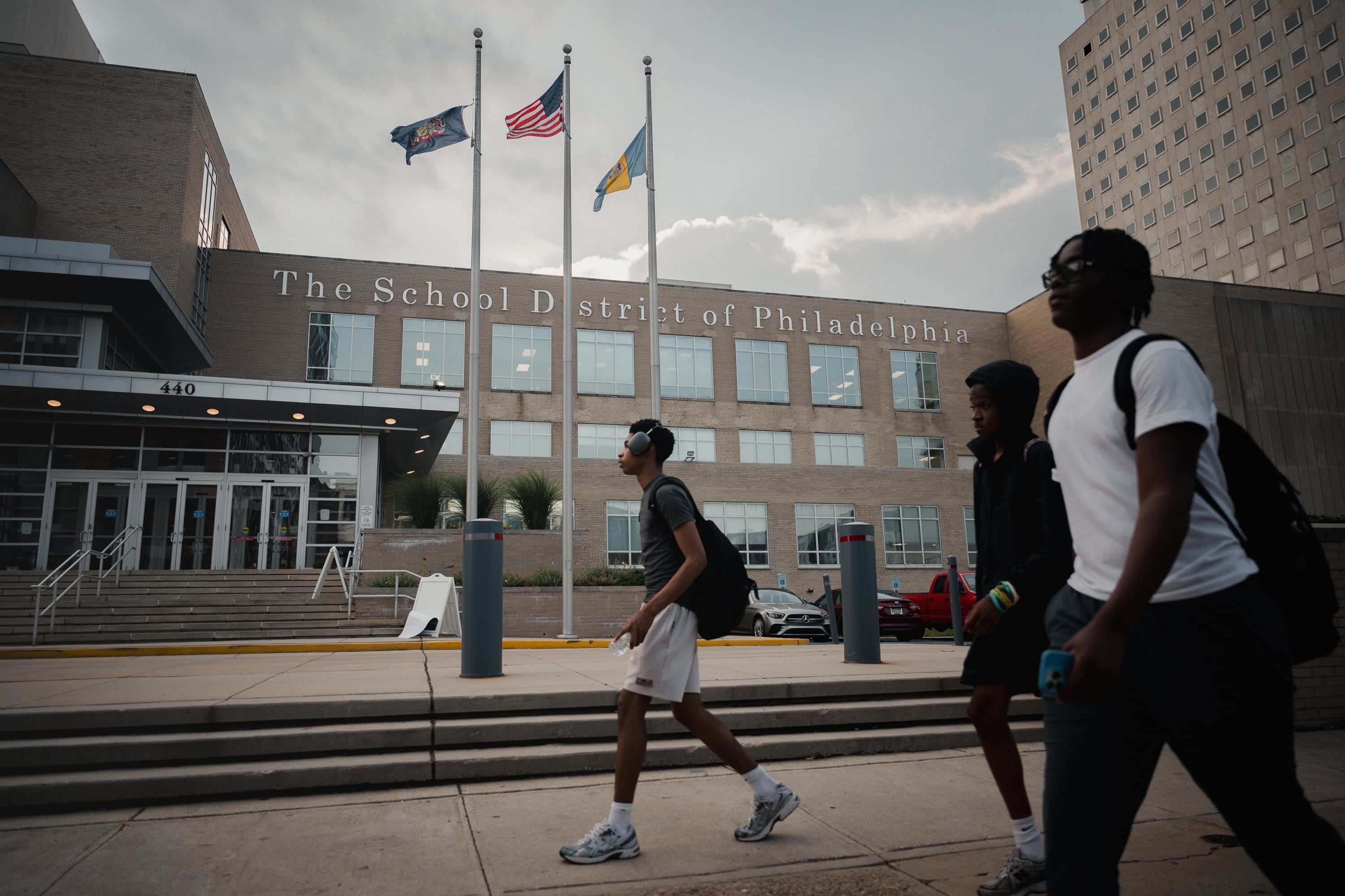 People walk by a sand-colored building.