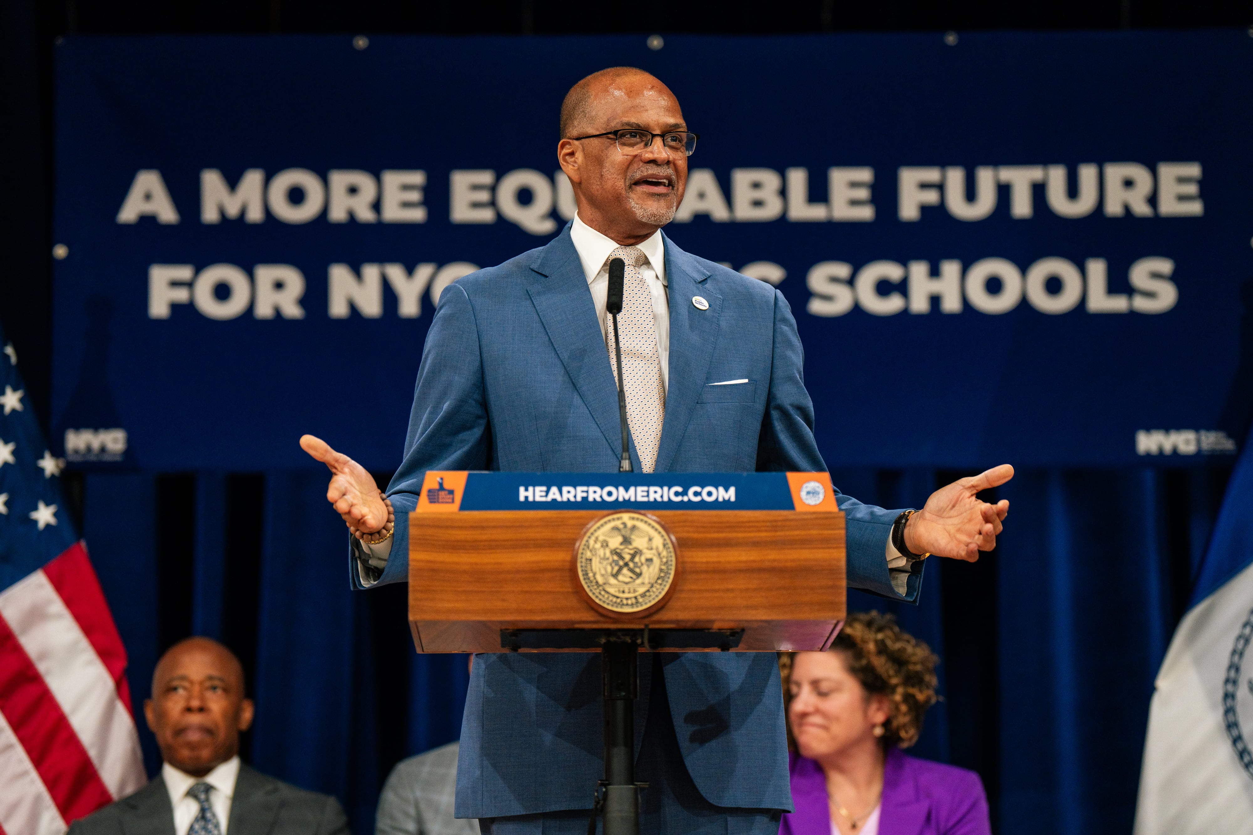 A man in a blue suit stands at a podium.
