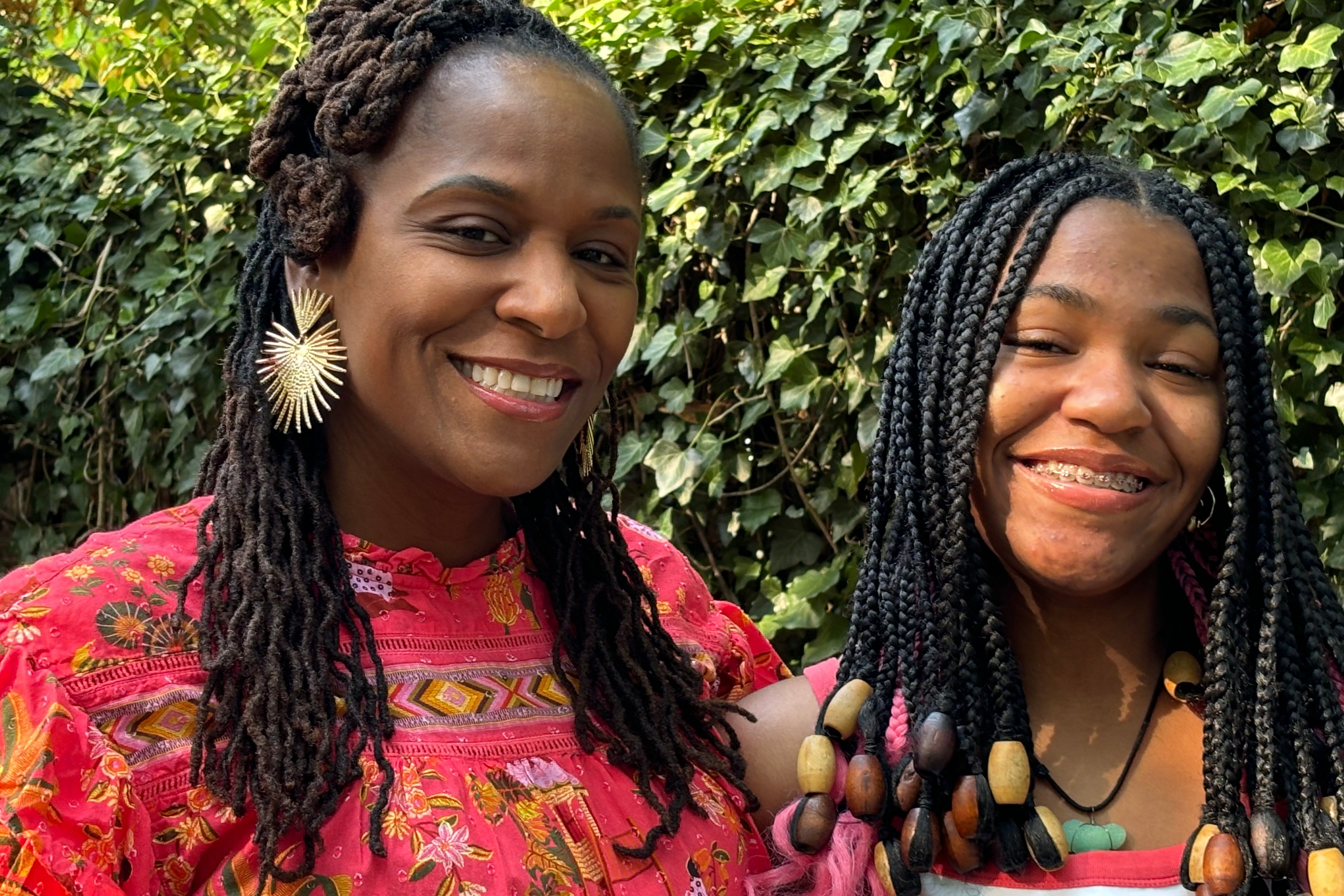 A woman in red stands next to a teenager in white.