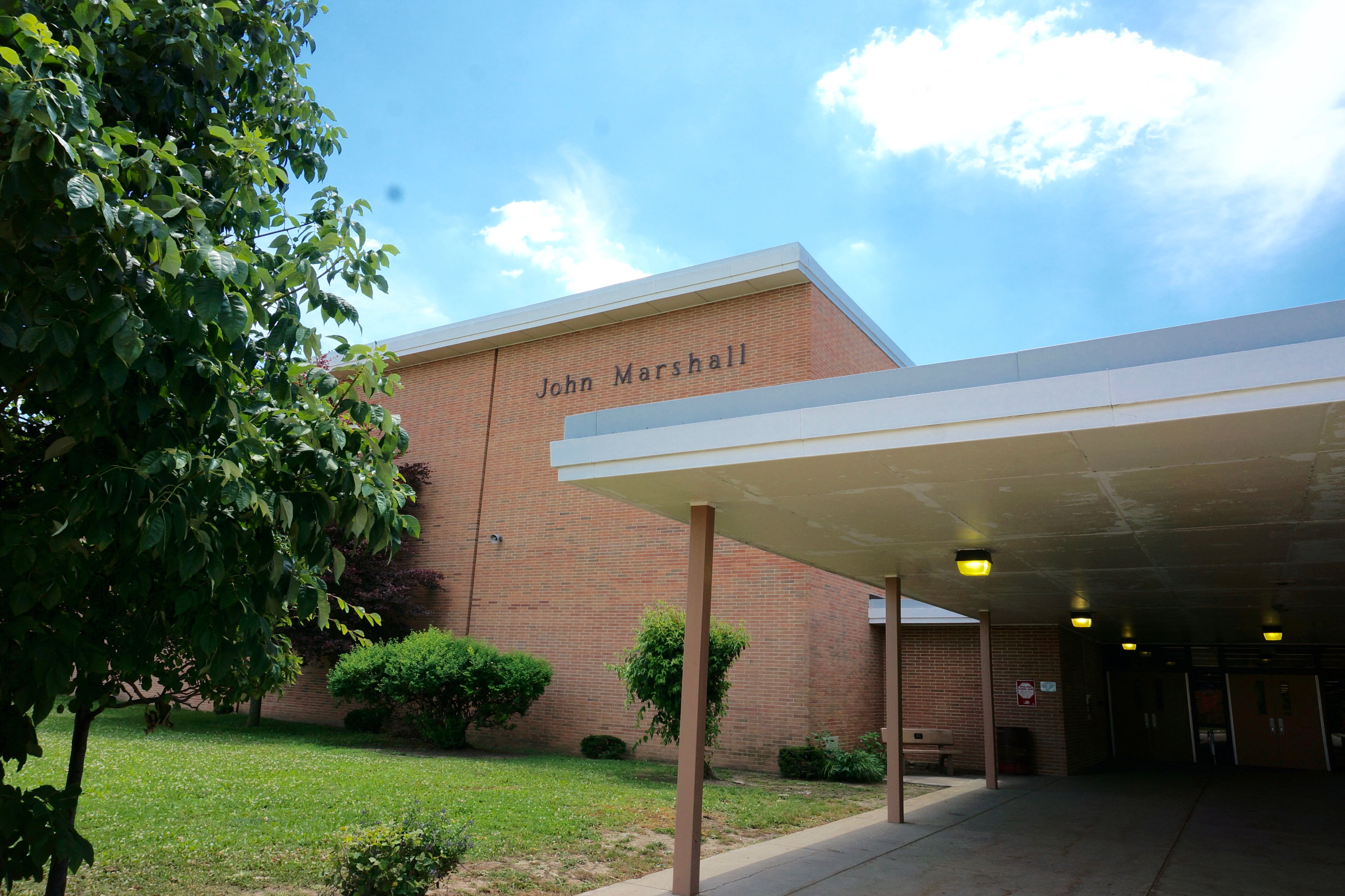 An exterior brick wall with the name John Marshall above an entrance corridor into a school.