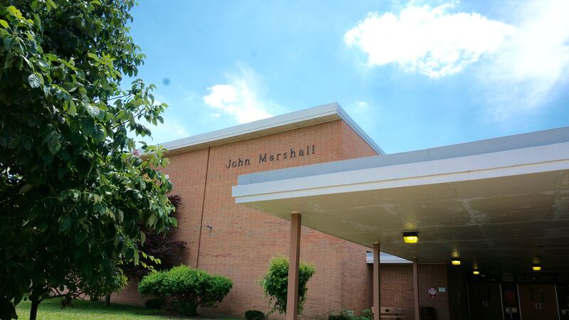 An exterior brick wall with the name John Marshall above an entrance corridor into a school.