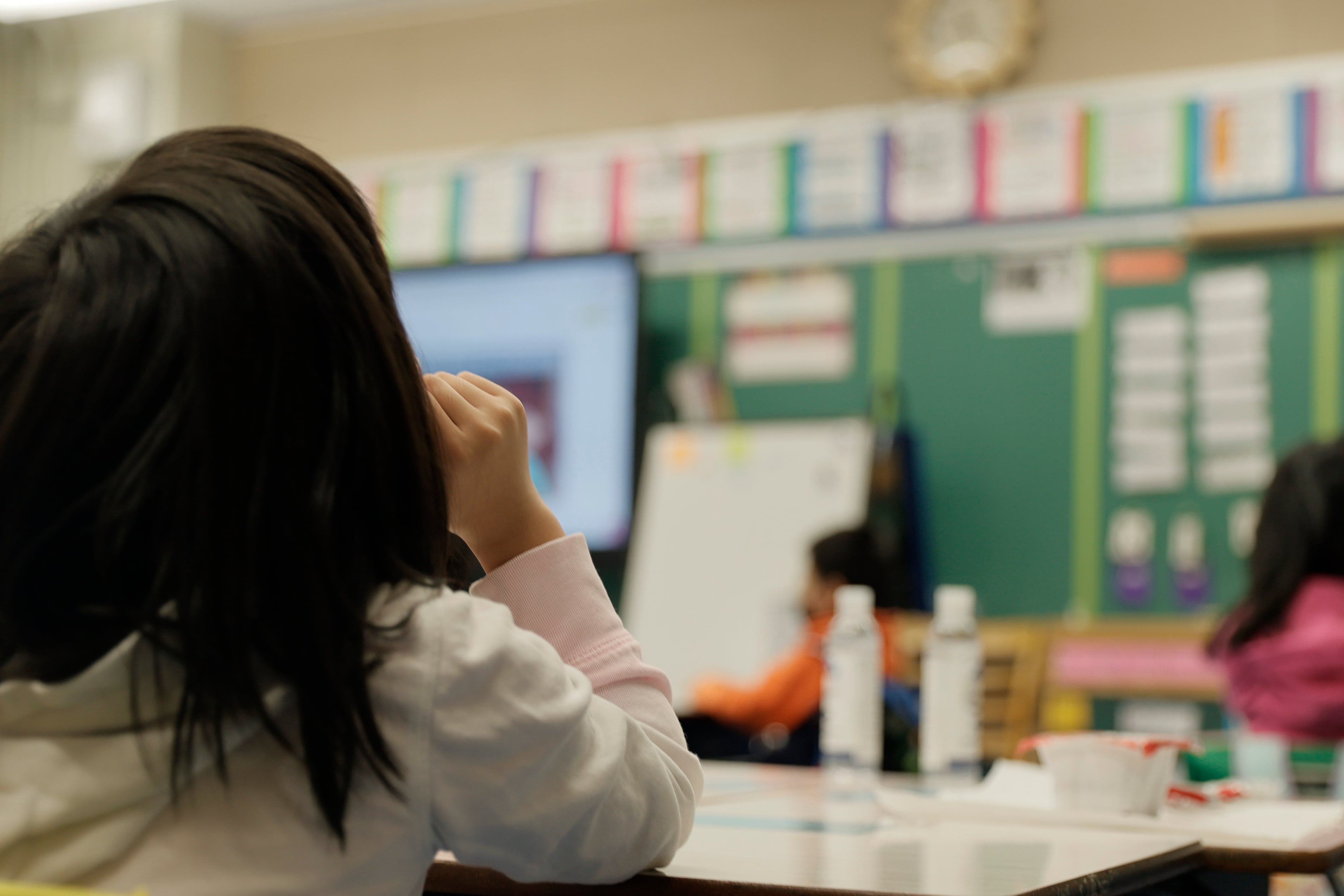 A child sits at a desk in a classroom.