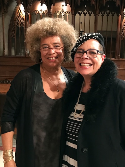 Two Black women stand next to each other and smile while posing for a photograph.