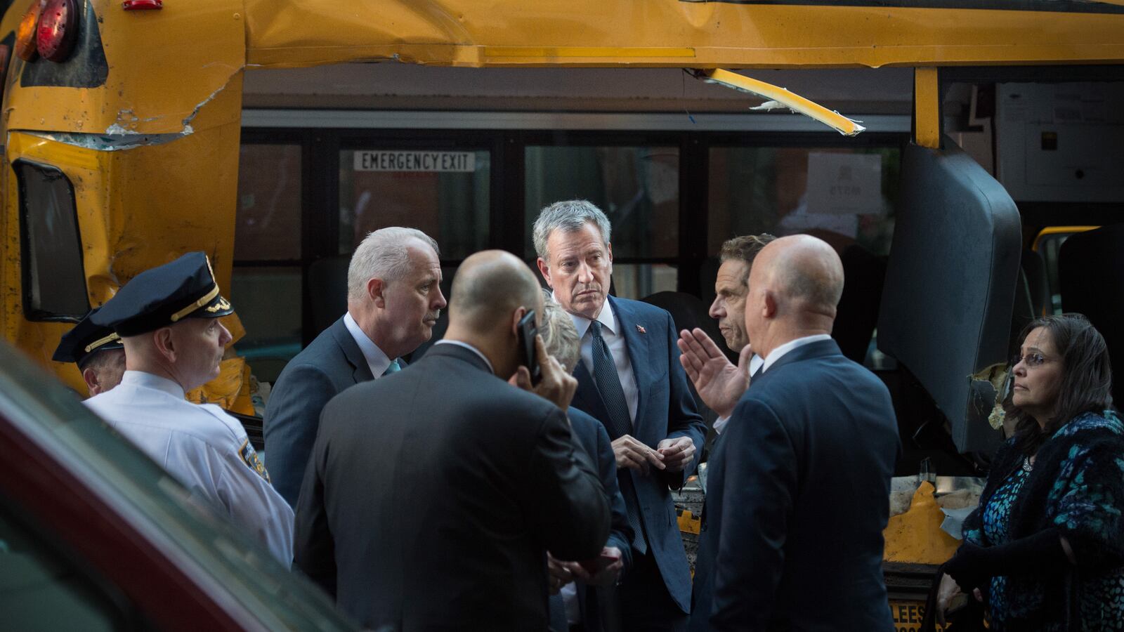 Mayor Bill de Blasio and Governor Andrew Cuomo stand in front of the school bus mangled in Tuesday's attack.
