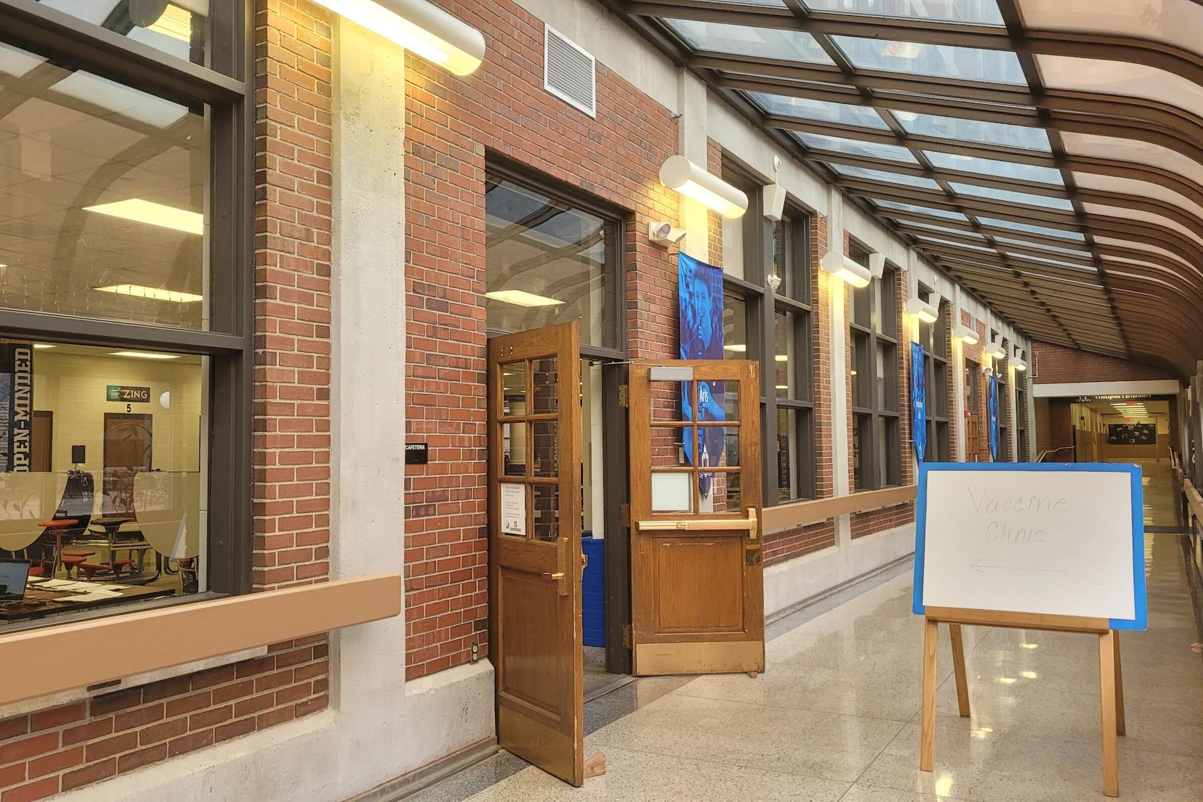 A sign on an easel says “Vaccination clinic” with an arrow pointing toward open French doors in building of Indianapolis Public Schools.