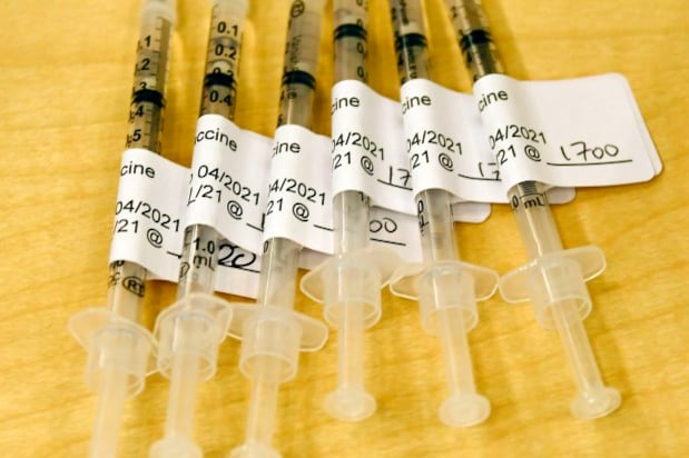 COVID-19 vaccine syringes sit on a table.