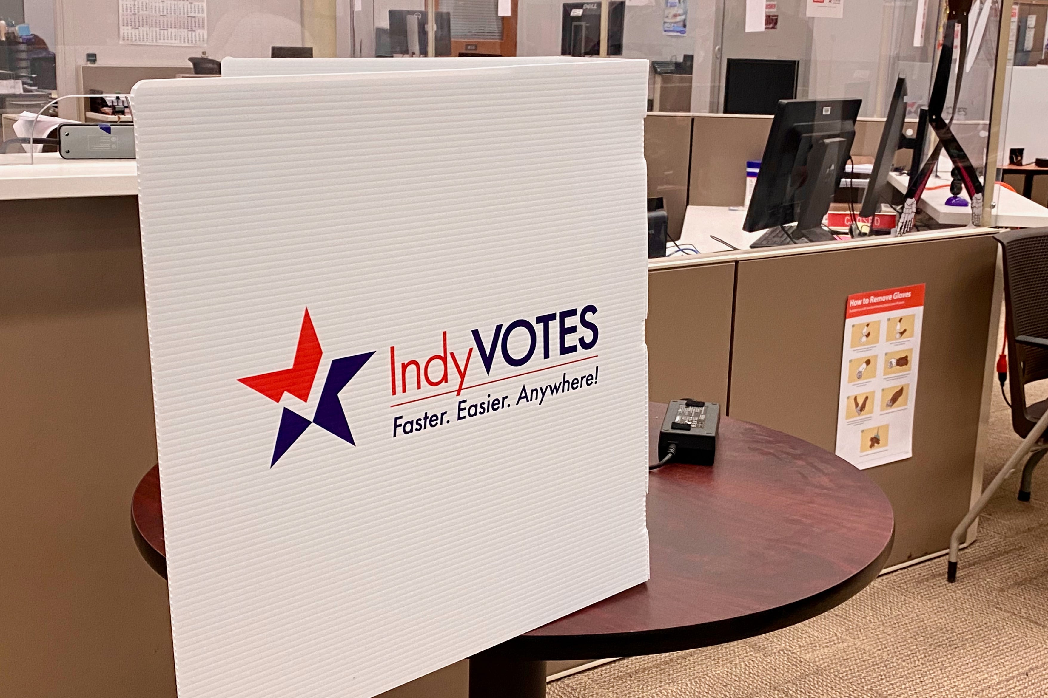 Voting privacy shield with “IndyVotes” printed on it.