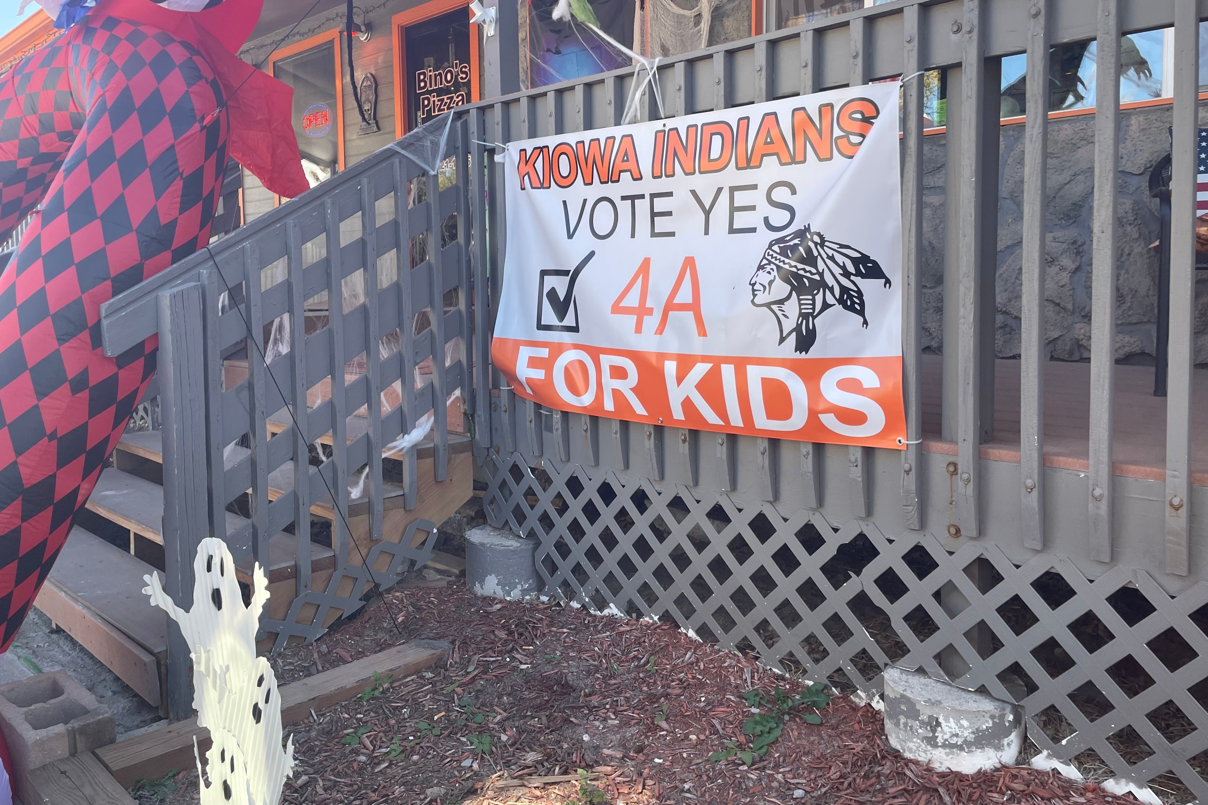An orange and white banner supporting a school district bond issue is attached to the front of a restaurant.