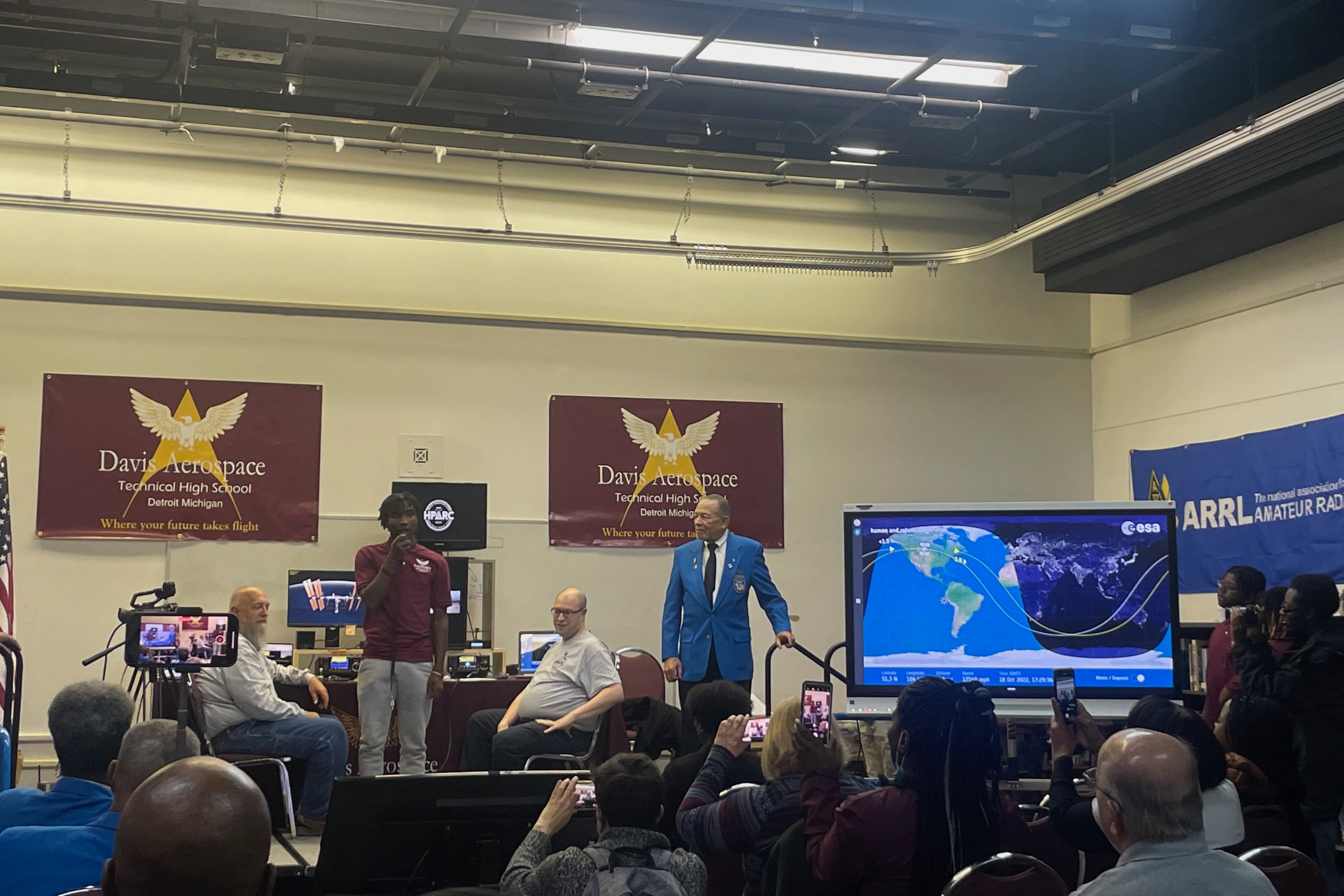 A young person speaks through a ham radio microphone on stage.