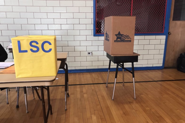 Two boxes for ballots stand in Yates Elementary in Chicago. A yellow box is for mail-in ballots dropped off at the campus and a brown box is for votes cast on site.
