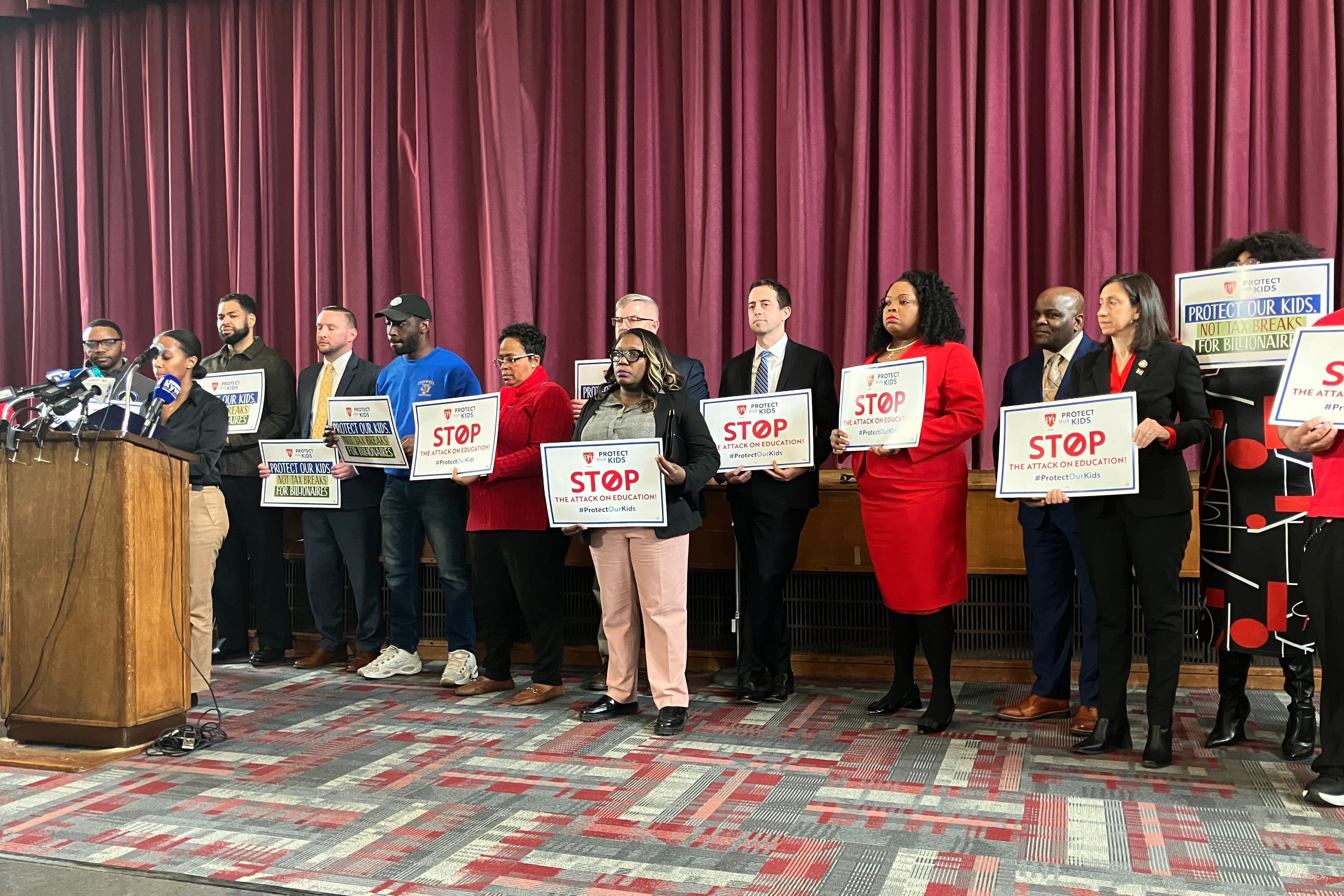 A group of people stand on stage holding signs.