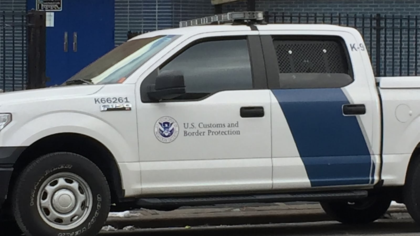 Two Customs and Border Patrol trucks parked outside of a school building in Washington Heights.
