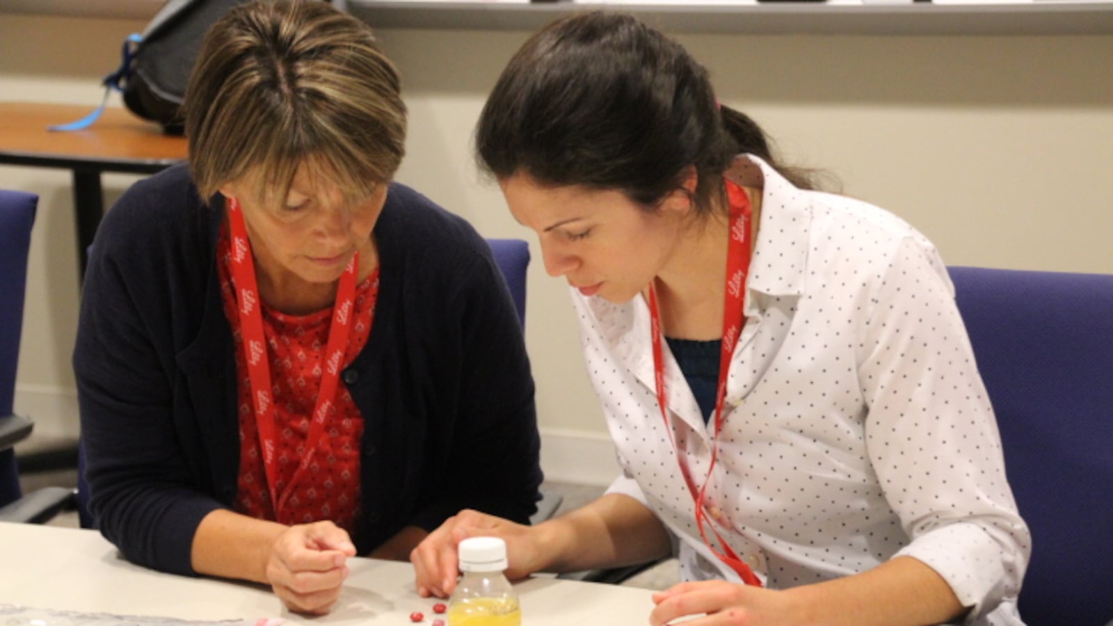 Teachers Paula Manchess (left) and Heidi Wilkinson (right) work to detect counterfeit medicines by creating a process to identify the correct color, shape, branding and purity of their samples.